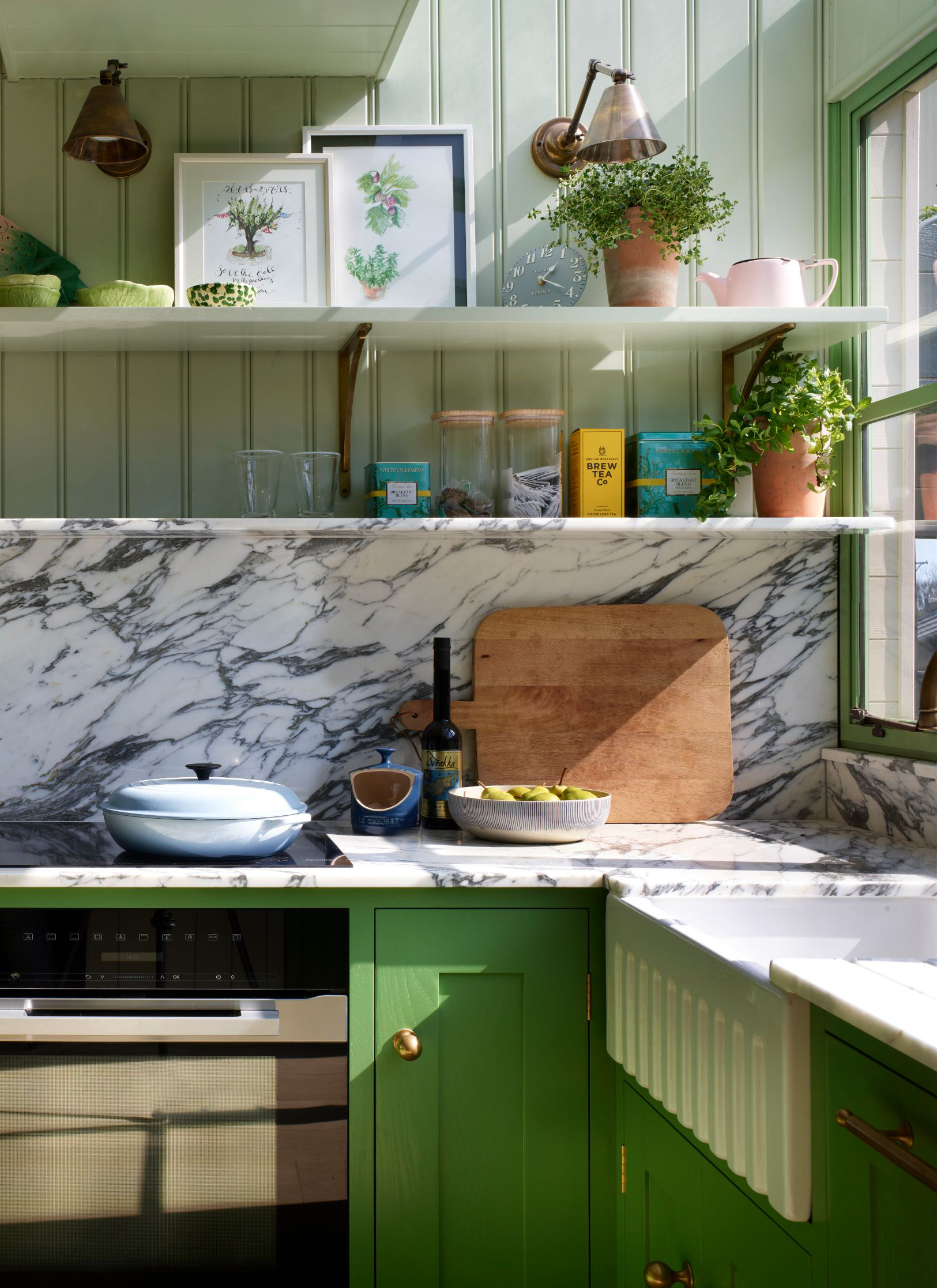 a kitchen with bright green cabinetry, white marble countertops and splashback and open shelving