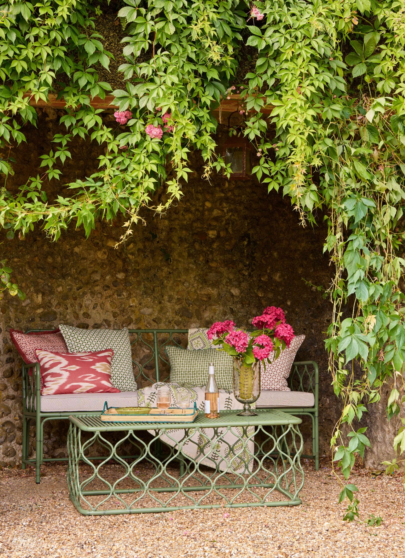 green rattan style bench and matching table beneath a canopy of leaves