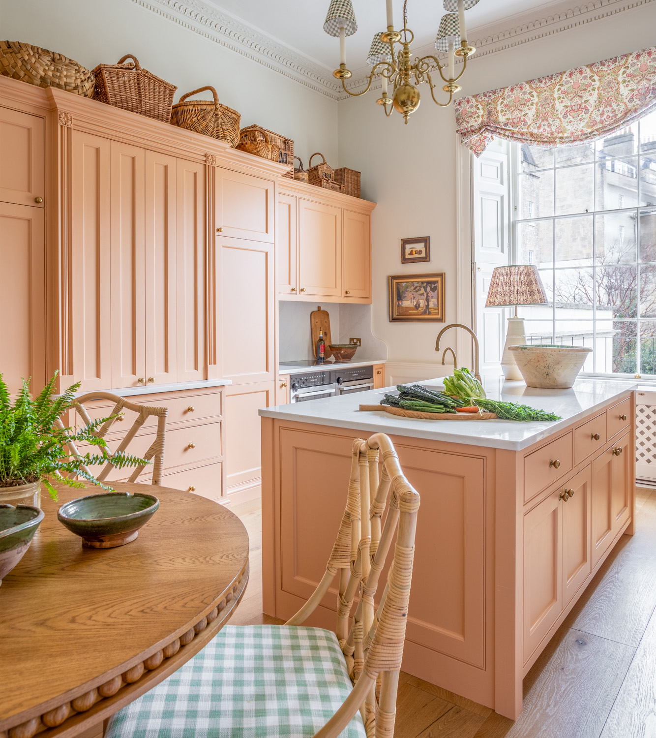 a kitchen with salmon pink cabinetry and kitchen island with a white marble top