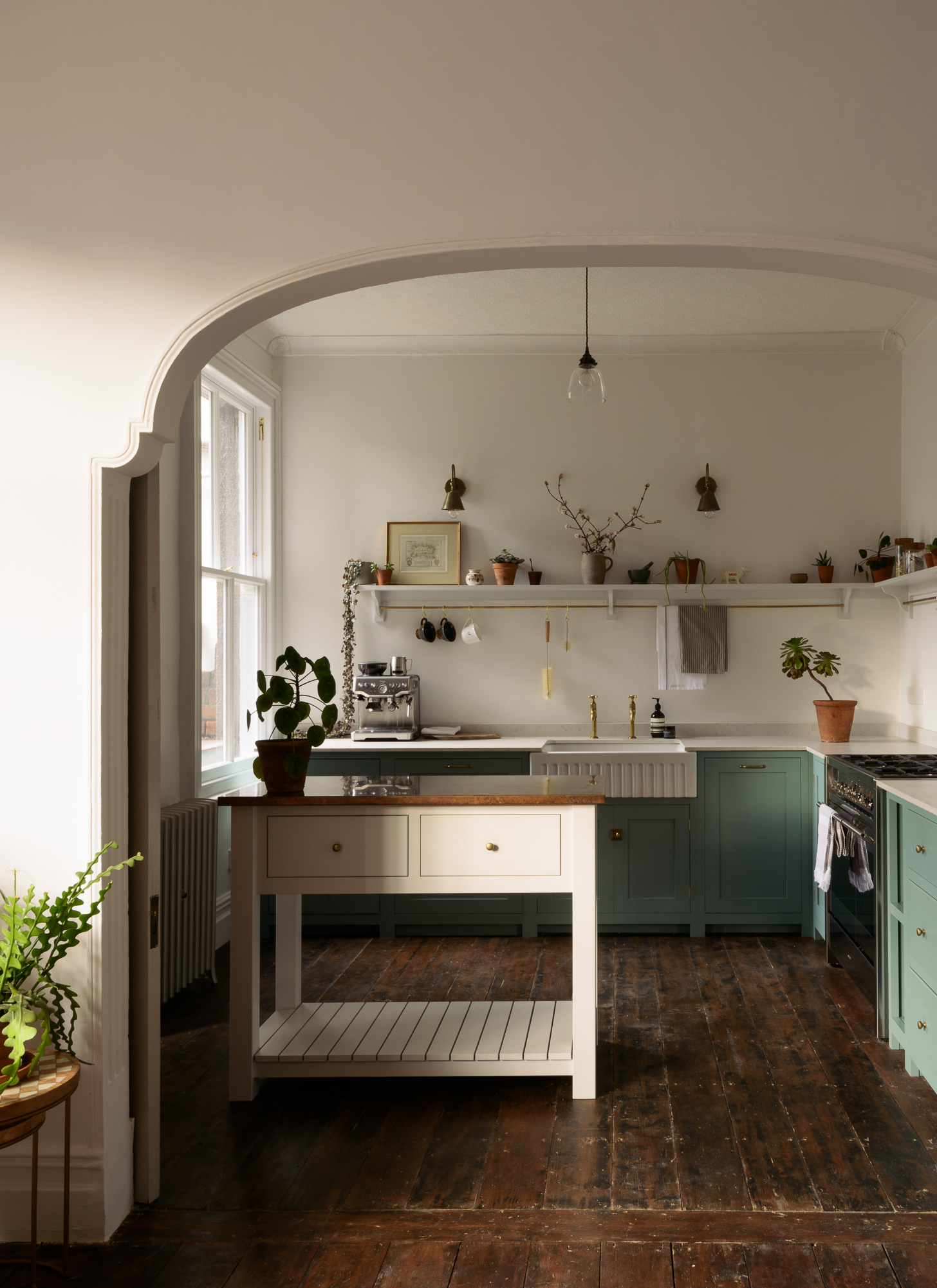 a kitchen with white walls, blue cabinetry, a small white kitchen island and wooden floors