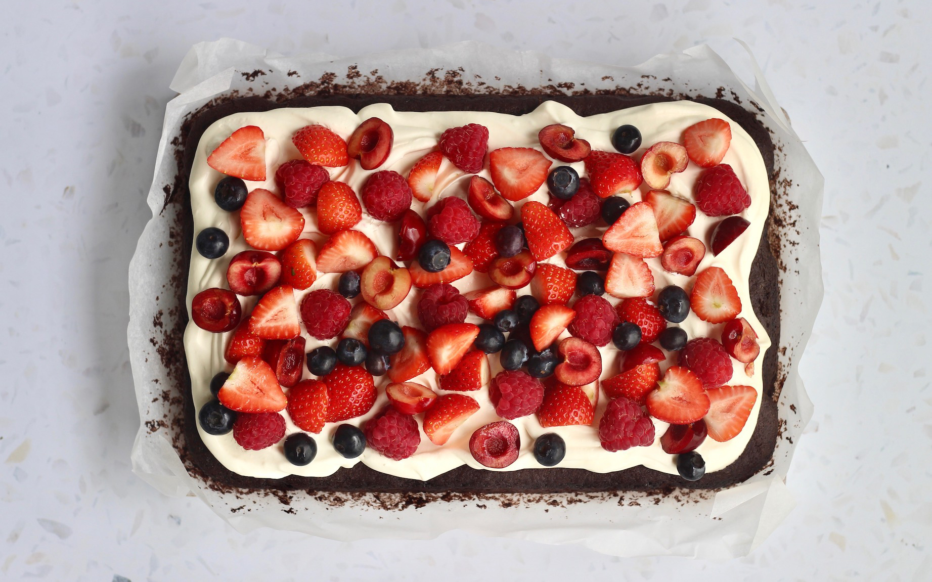a chocolate cake with cream, strawberries, raspberries and berries