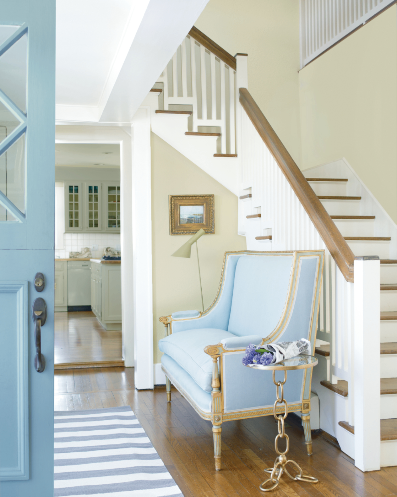 a beige an white hallway with a pale blue front door and a pale blue armchair