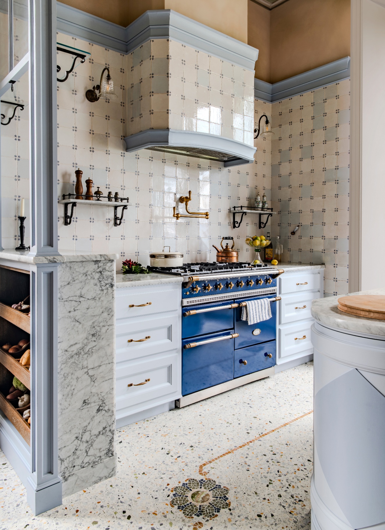 a kitchen with terrazzo floor, pale blue cabinetry, a bright blue range cooker and white and blue tiled walls and extractor hood