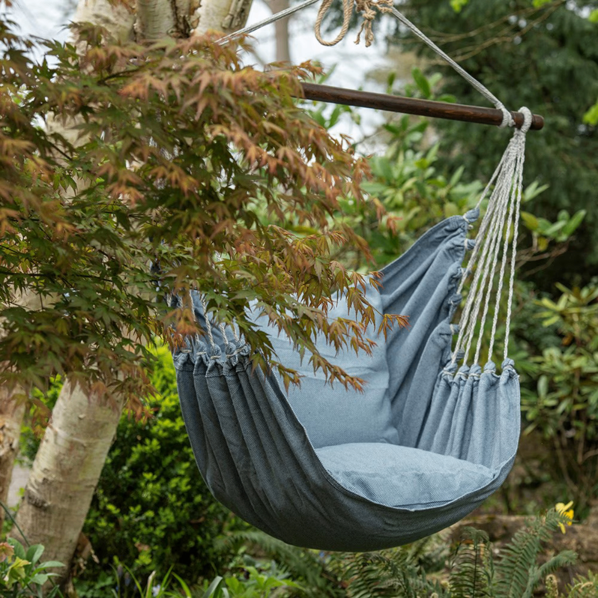 a blue hammock chair hung from a tree