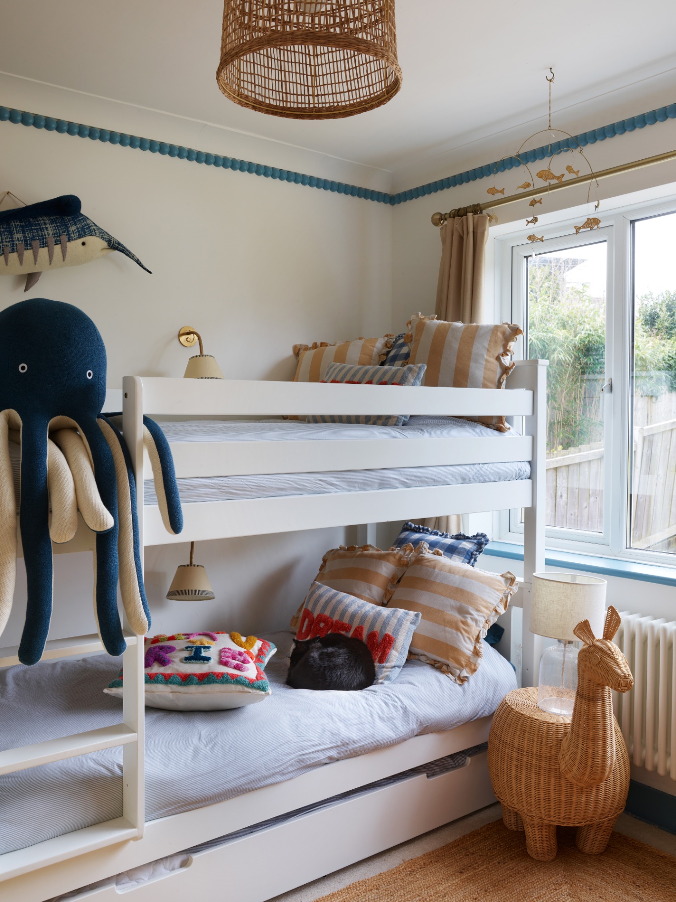 a childrens bedroom with white walls and white bunkbeds with a large blue octopus soft toy