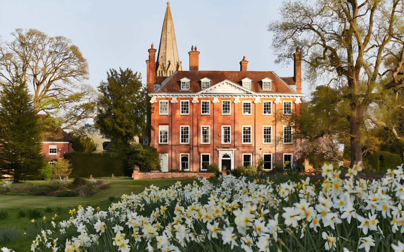 the exterior of welford park surrounded by green lawns and yellow daffodils