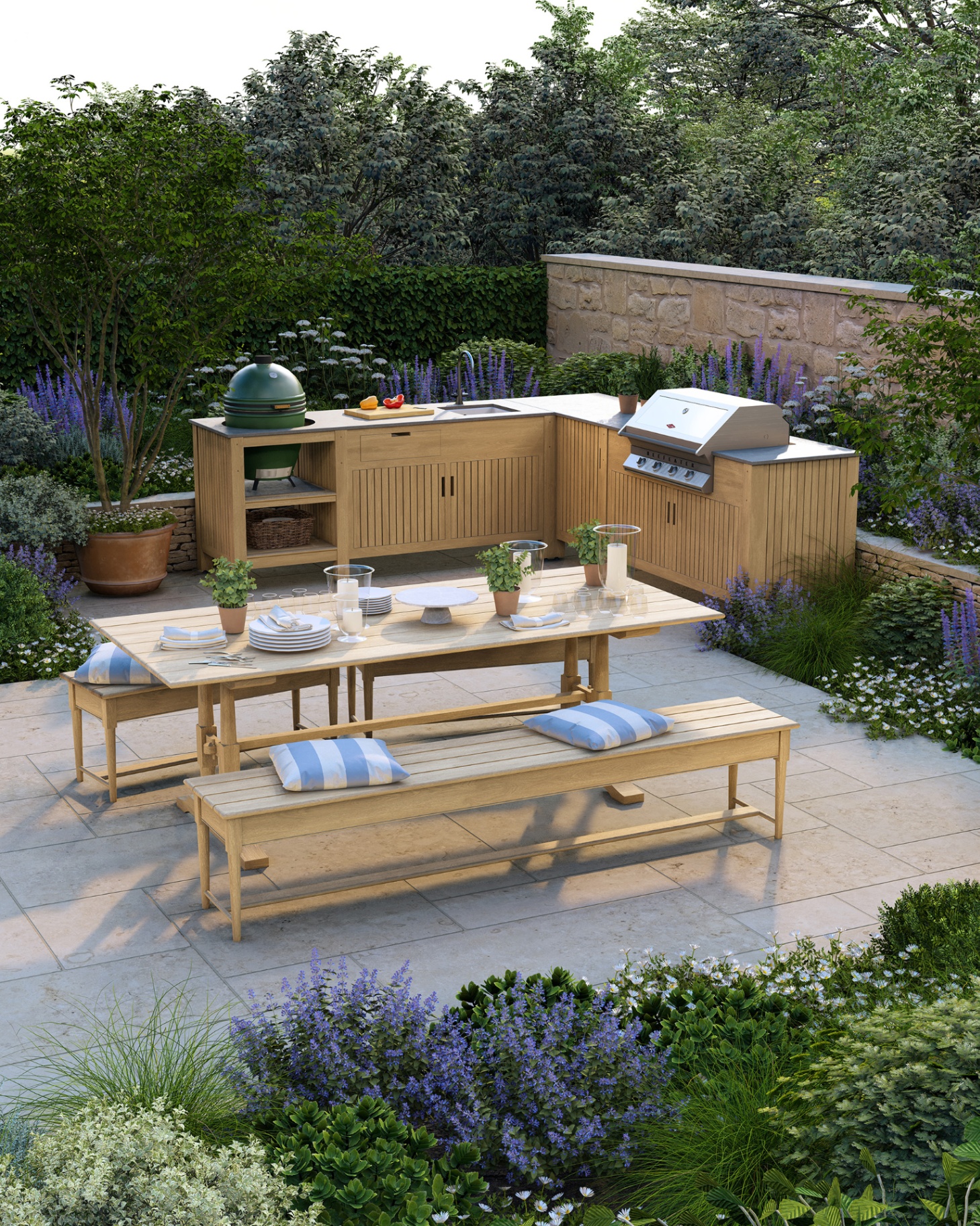 an outdoor kitchen area surrounded by bushes and flowers with a dining table in the centre with benches with striped blue and white cushions on top