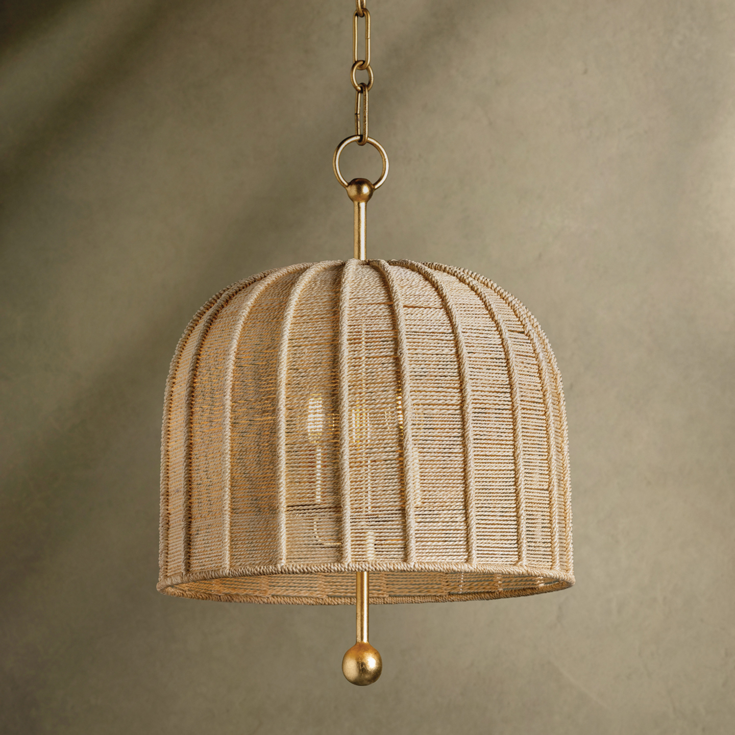 a cream pendant light with gold hardware on a moss green background