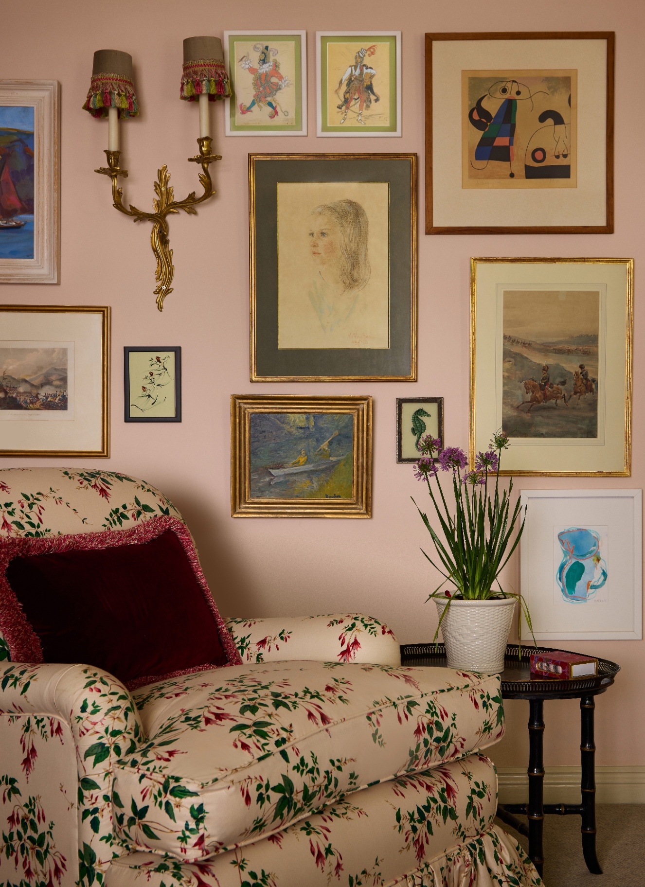 a close up of a cream and green botanical printed armchair against a pale pink wall with a gallery wall