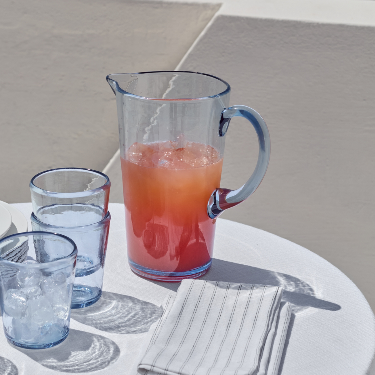 A CLEAR BLUG PICNIC JUG ON A WHITE ROUND TABLE