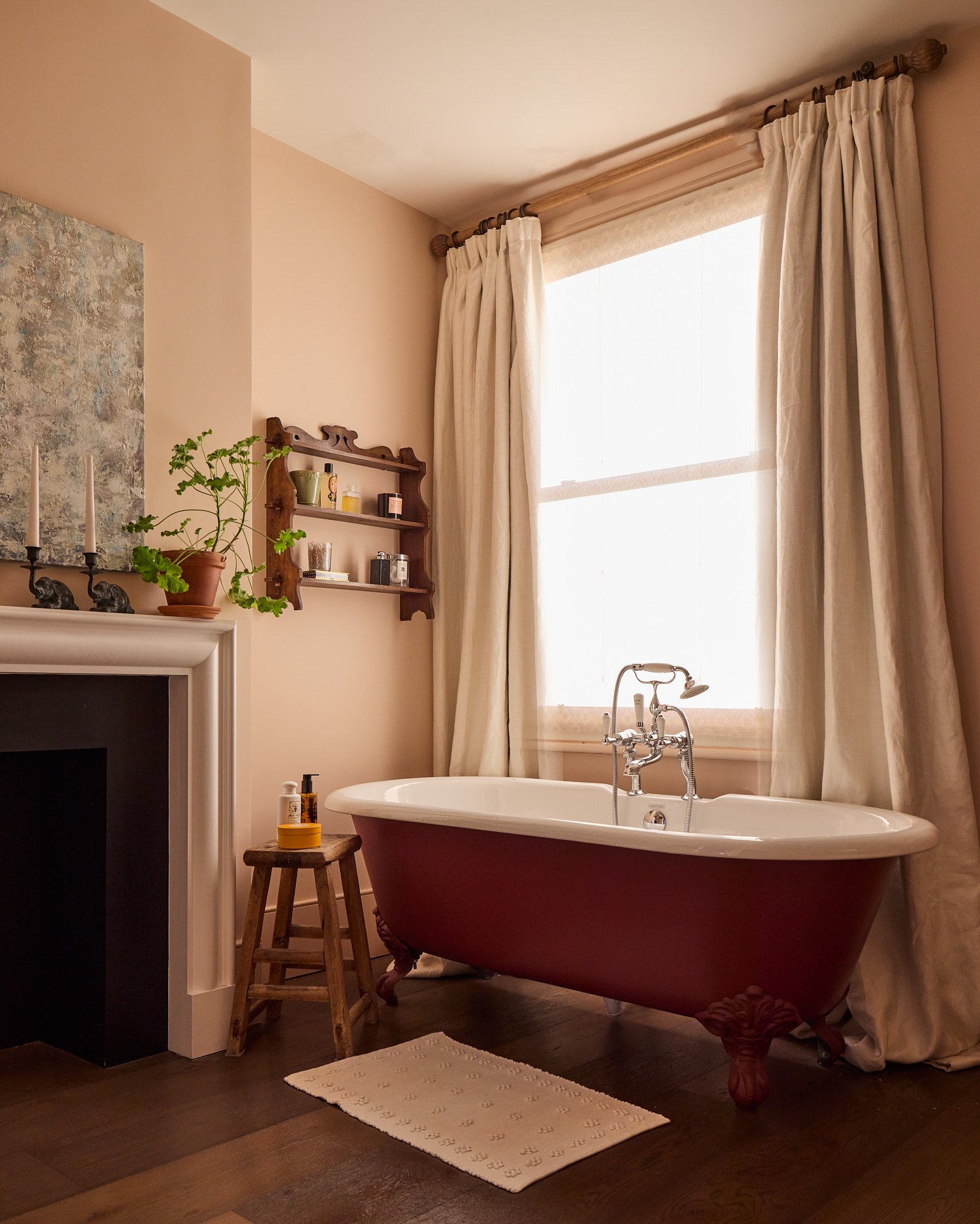 a bathroom pictured with a roll top bath and heavy draped curtains inspired by living rooms can be seen next to a fireplace with a picture on the wall