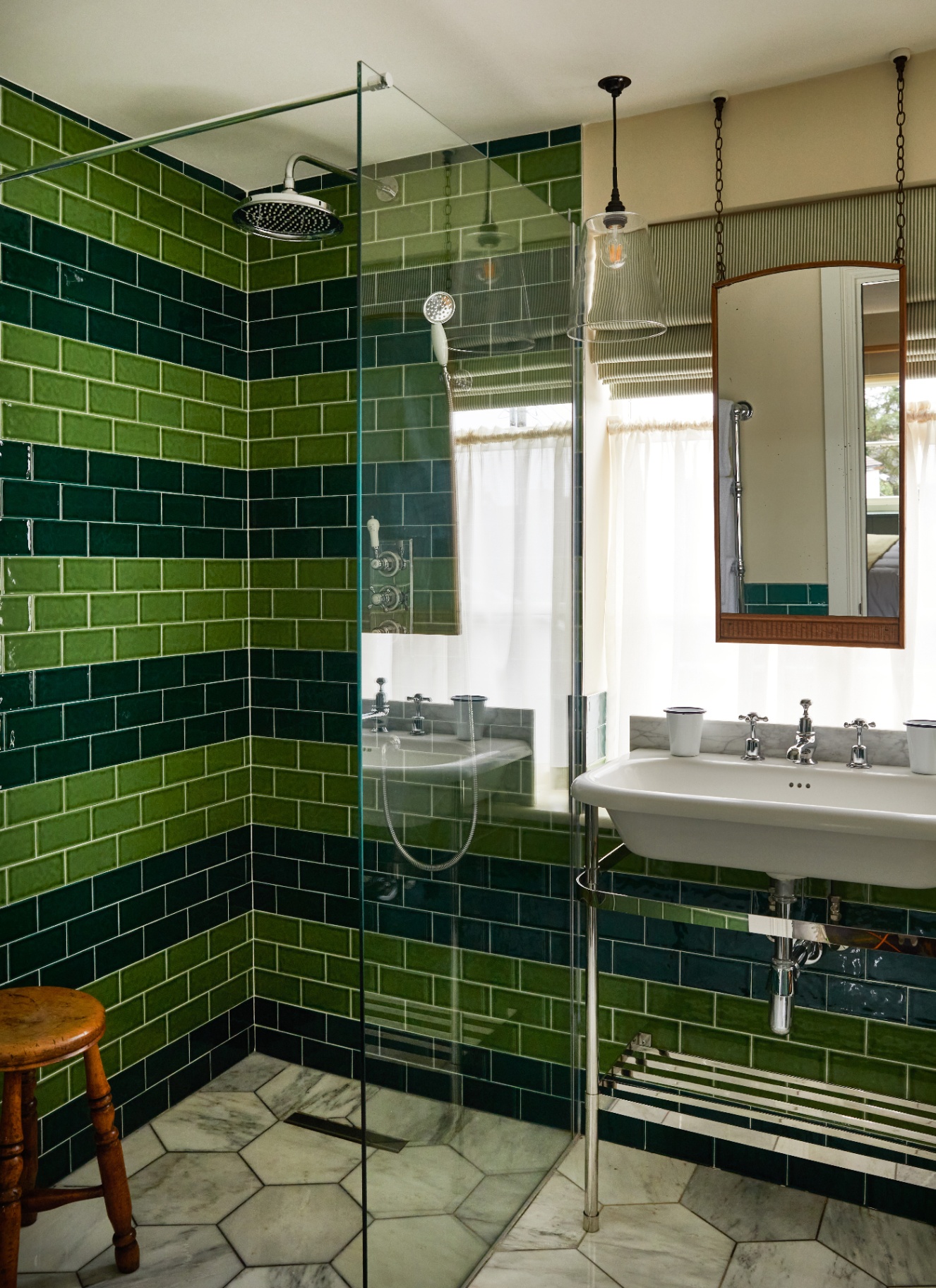 a bathroom with a walk in shower with bright green and dark green tiles laid out in a stripe pattern