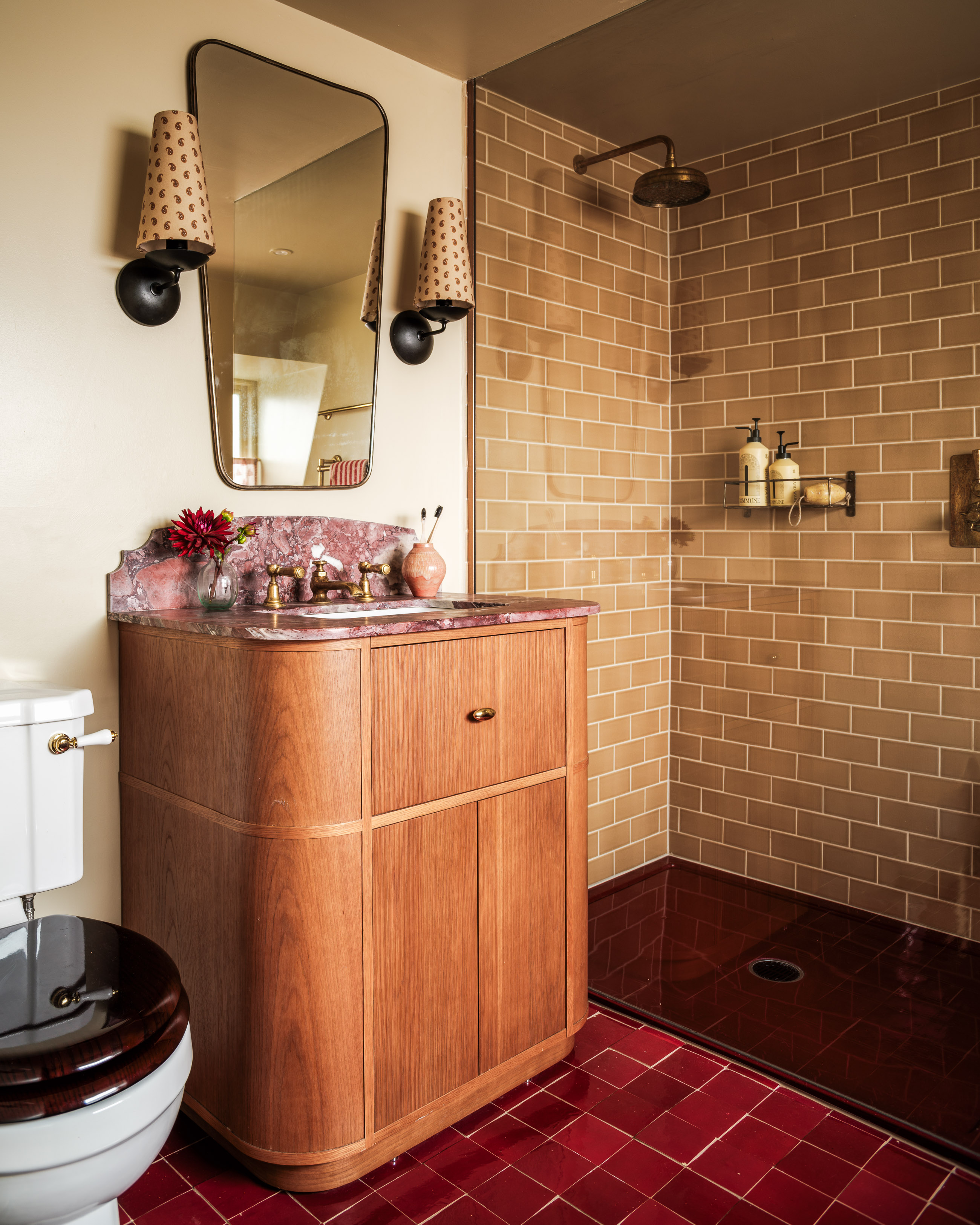 a small bathroom vanity pictured in dark timber wood with a vintage mirror hanging above it, on the floor are statement bathroom bright tiles