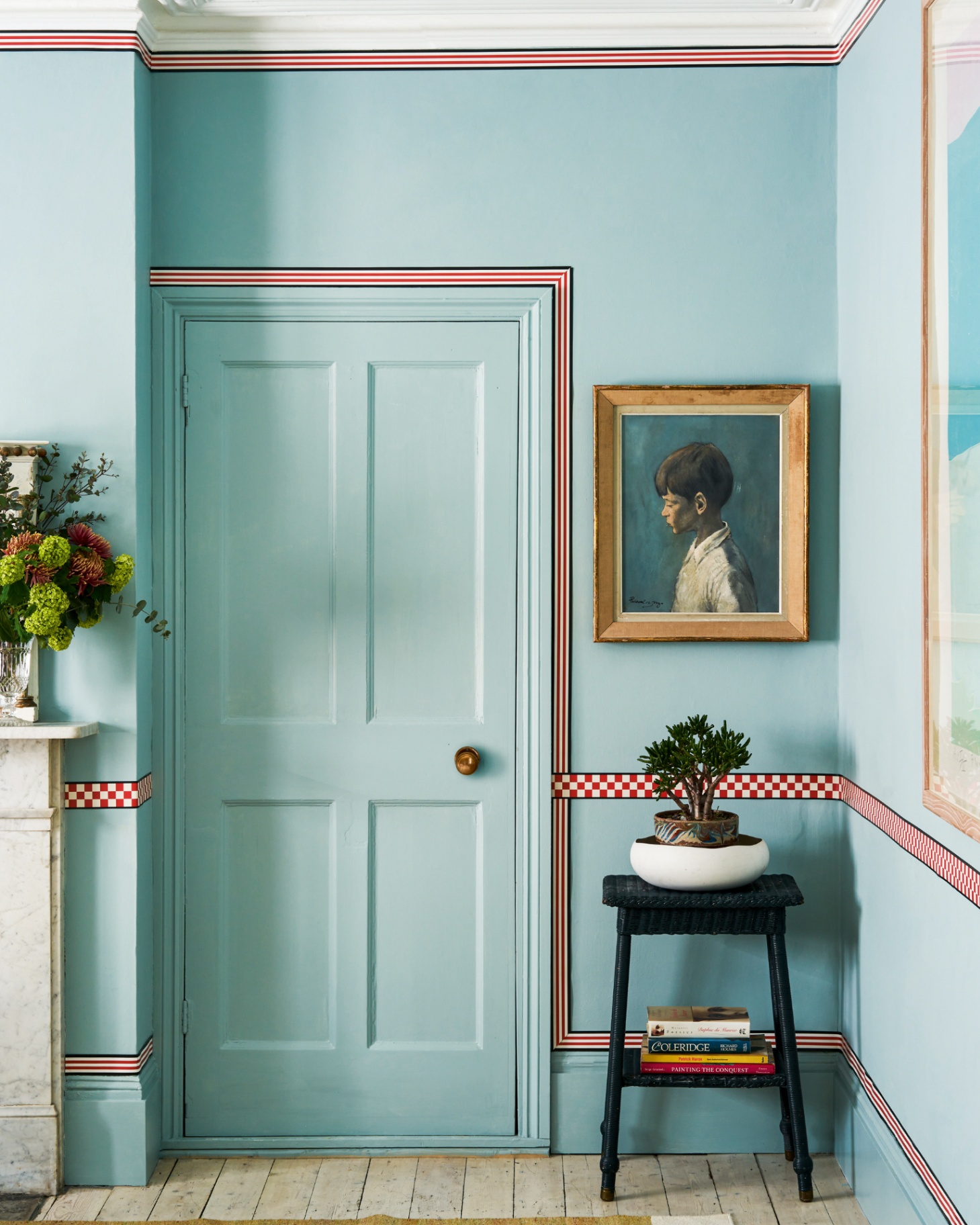 a room with a blue painted door and walls with a red, black and white striped border around the door, skirting board and ceiling