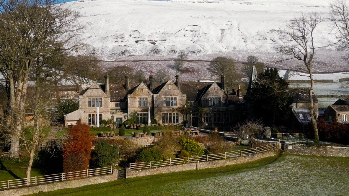 Simonstone Hall hotel, Hawes. An Elizabethan house with a garden out the front and a snow covered hill behind in Yorkshire