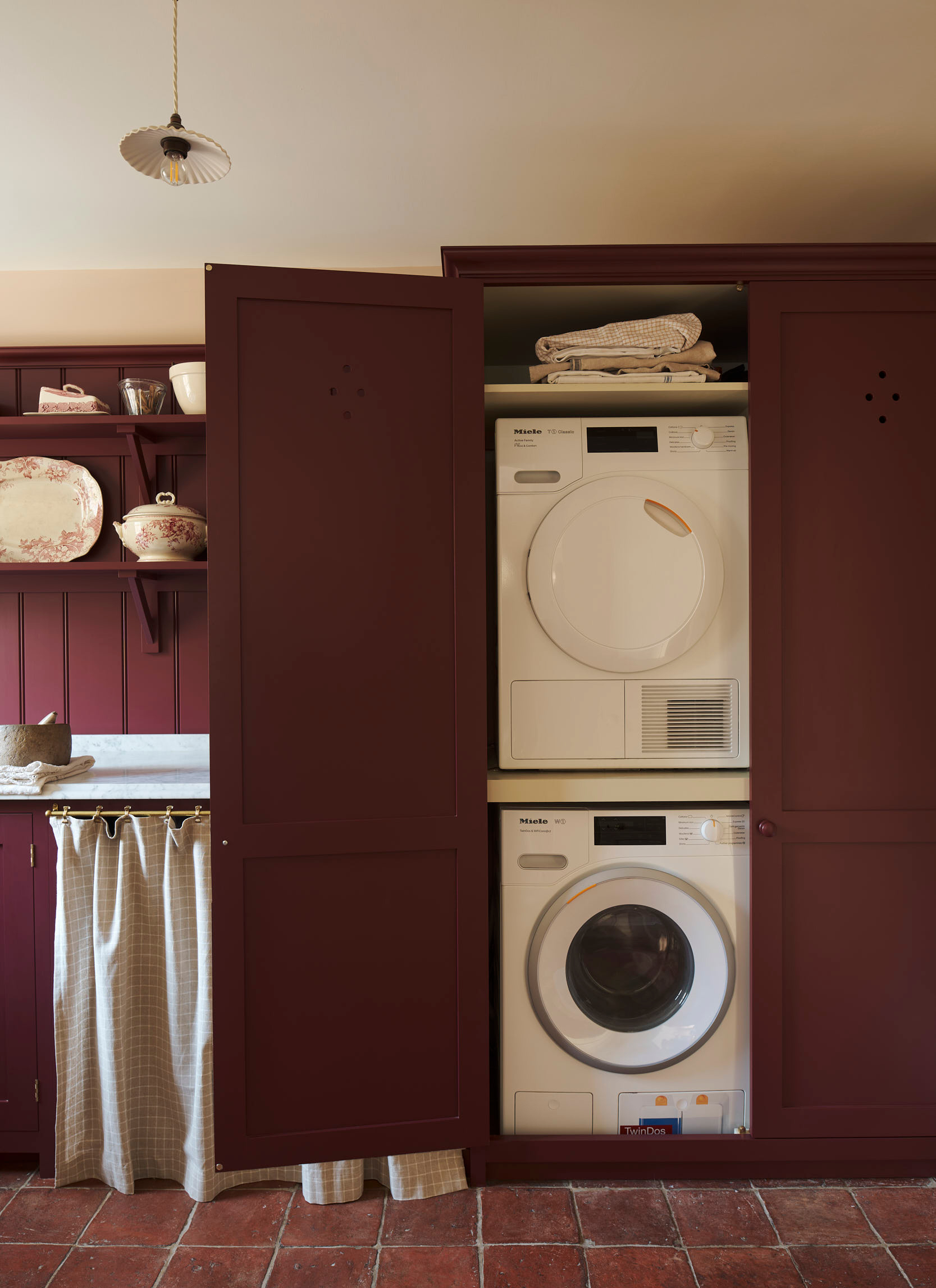 a laundry utility room with dark red cabinets and walls and two stacked washing machines