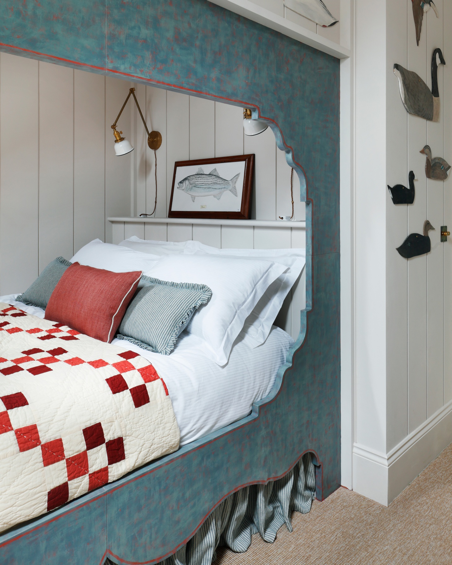 a cabin bed painted in blue with a striped skirt beneath and duck paintings on the wall