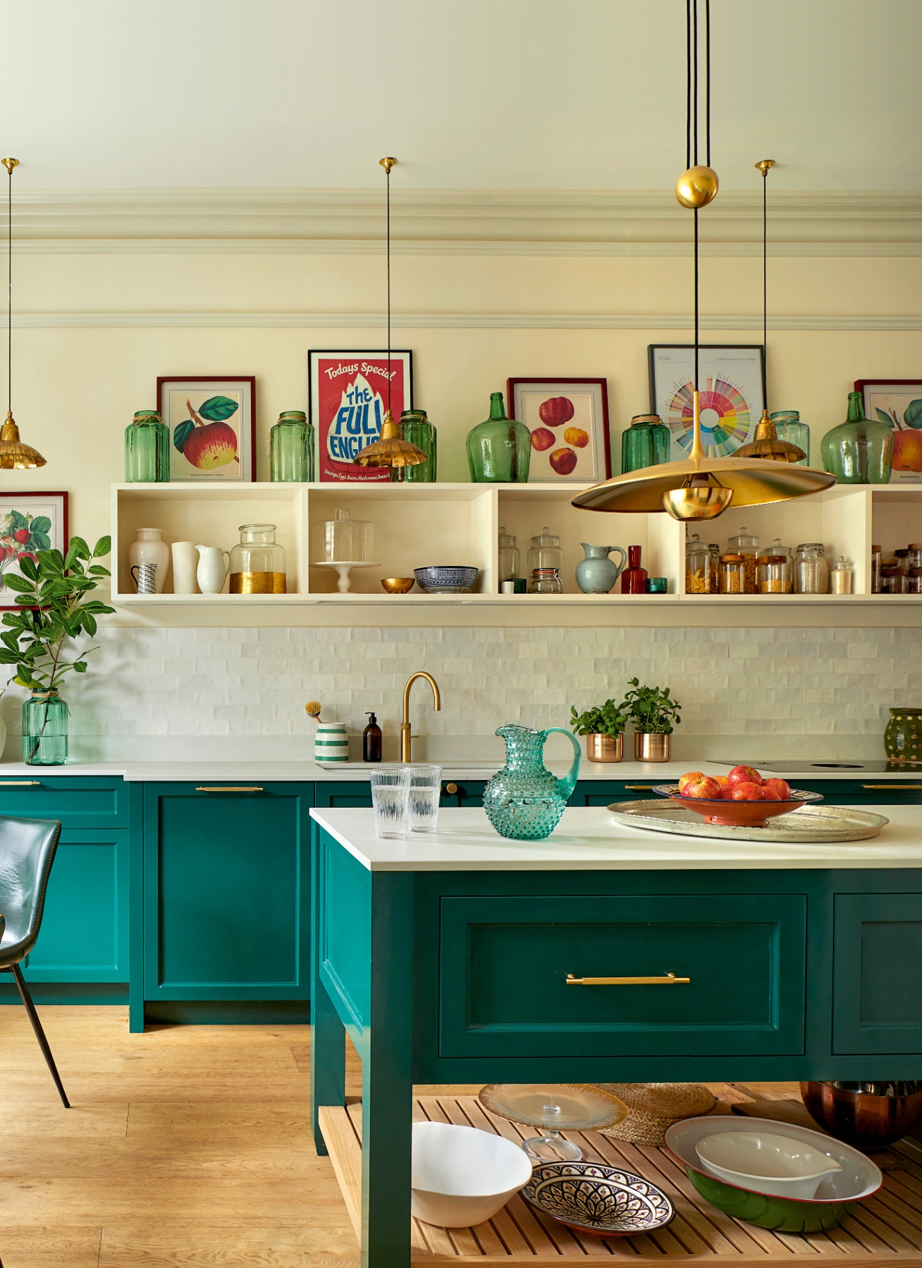 a kitchen with teal cabinetry, gold pendants and large cream open shelves filled with artwork and vases