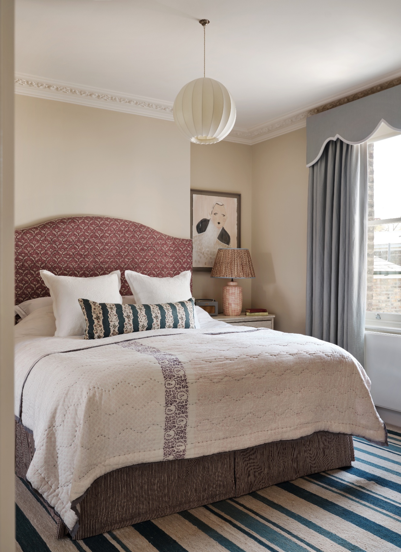 A bedroom with a pale sage painted ceiling and ceiling rose, featuring a ribbed paper saucer-shaped pendant light.