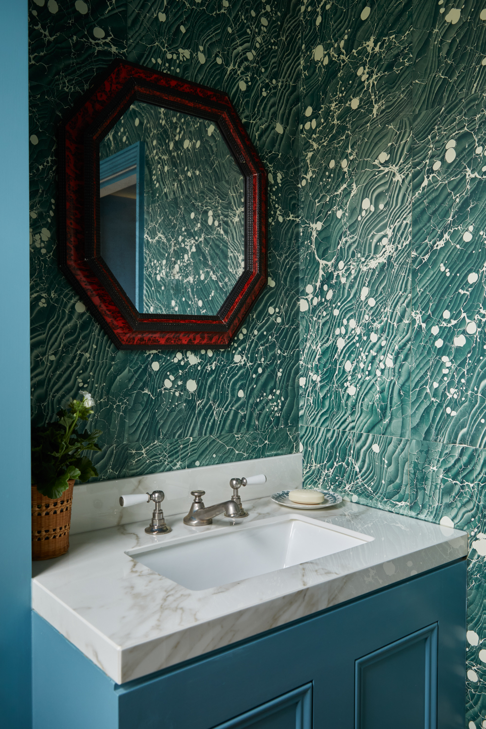 a small bathroom vanity pictured with marble detailing and a vintage mirror sitting above it