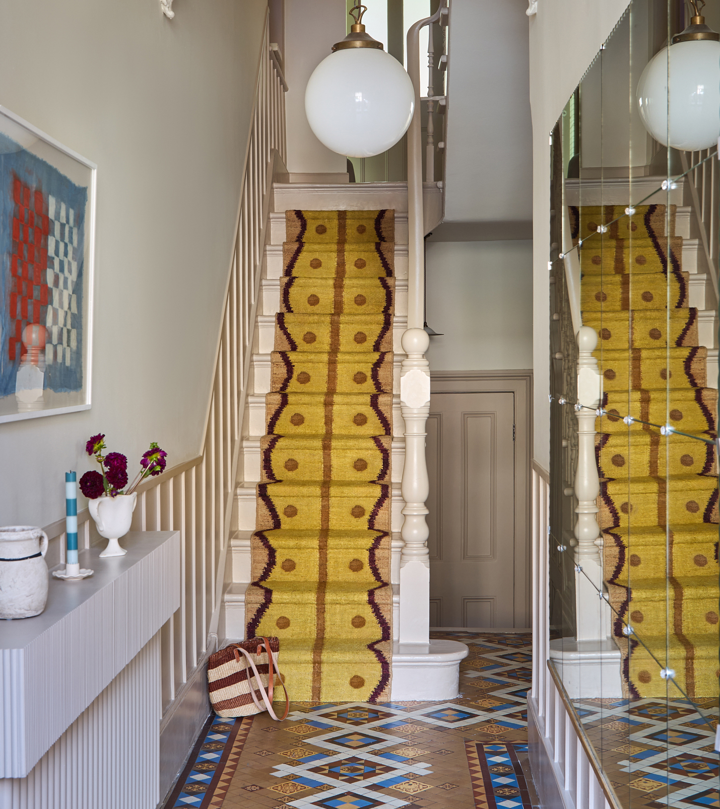 a white hallway with a mustard yellow patterned runner on the stairs and a brown patterned floor