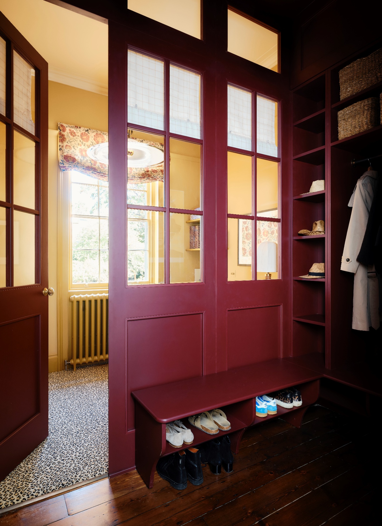 a boot room with built in shelves and cabinets colour drenched in a deep red colour