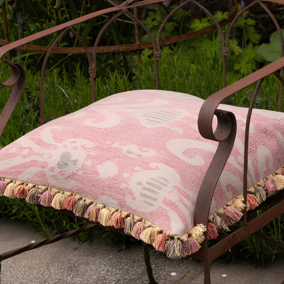 susie watson Faded Rose Natasha Cushion pictured on a bistro chair in a garden
