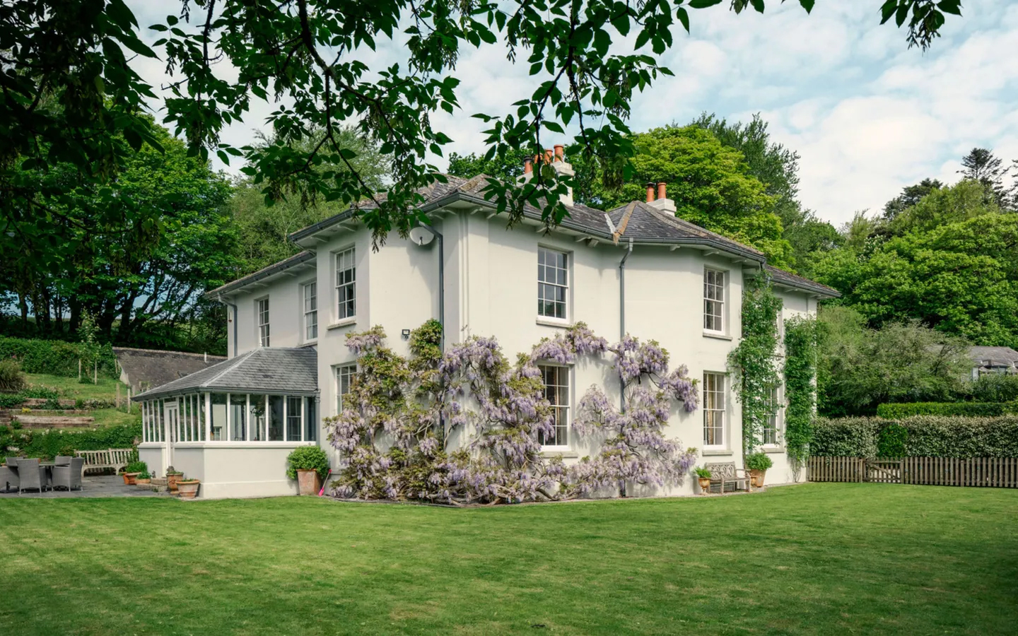 the exterior of a white house covered in wisteria