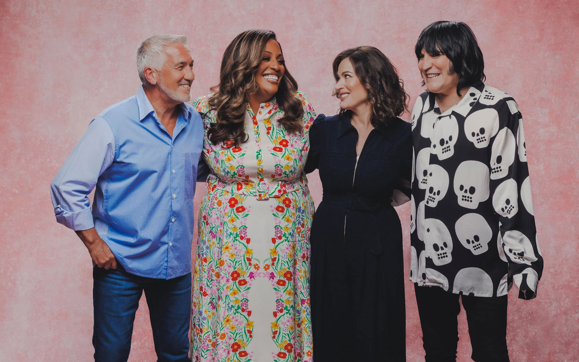 The Great British Bake off 2026 season 17 cast judges pictured nigella lawson paul hollywood alison hammond noel fielding smiling against a pink backrgound