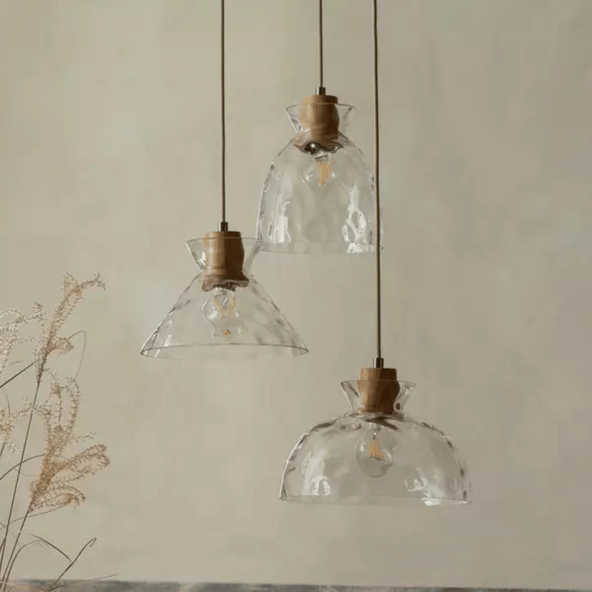 a cluster of three pendant lights with dimpled clear glass shades of different shapes