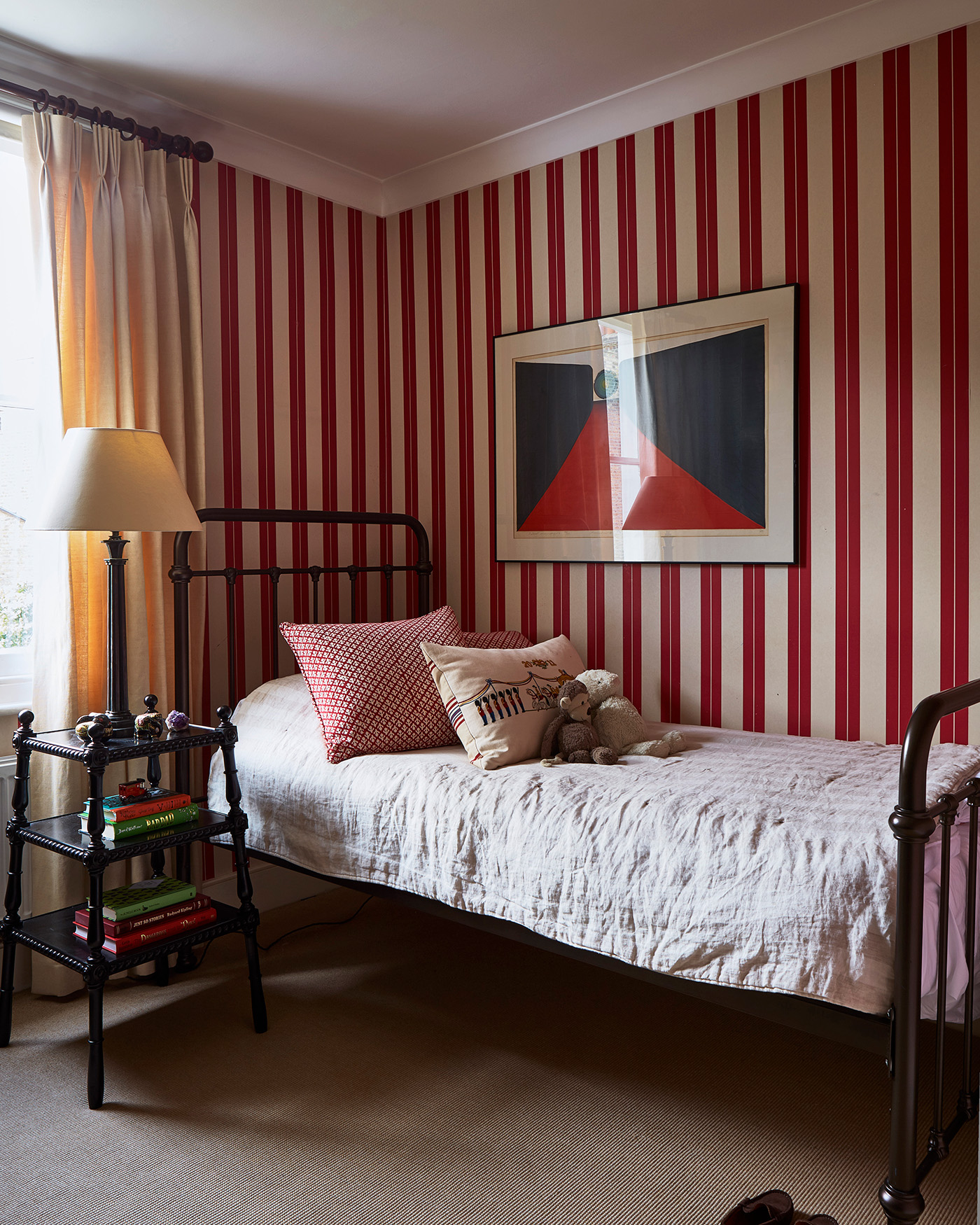 a childrens bedroom with white and red striped wallpaper and a black iron bed frame