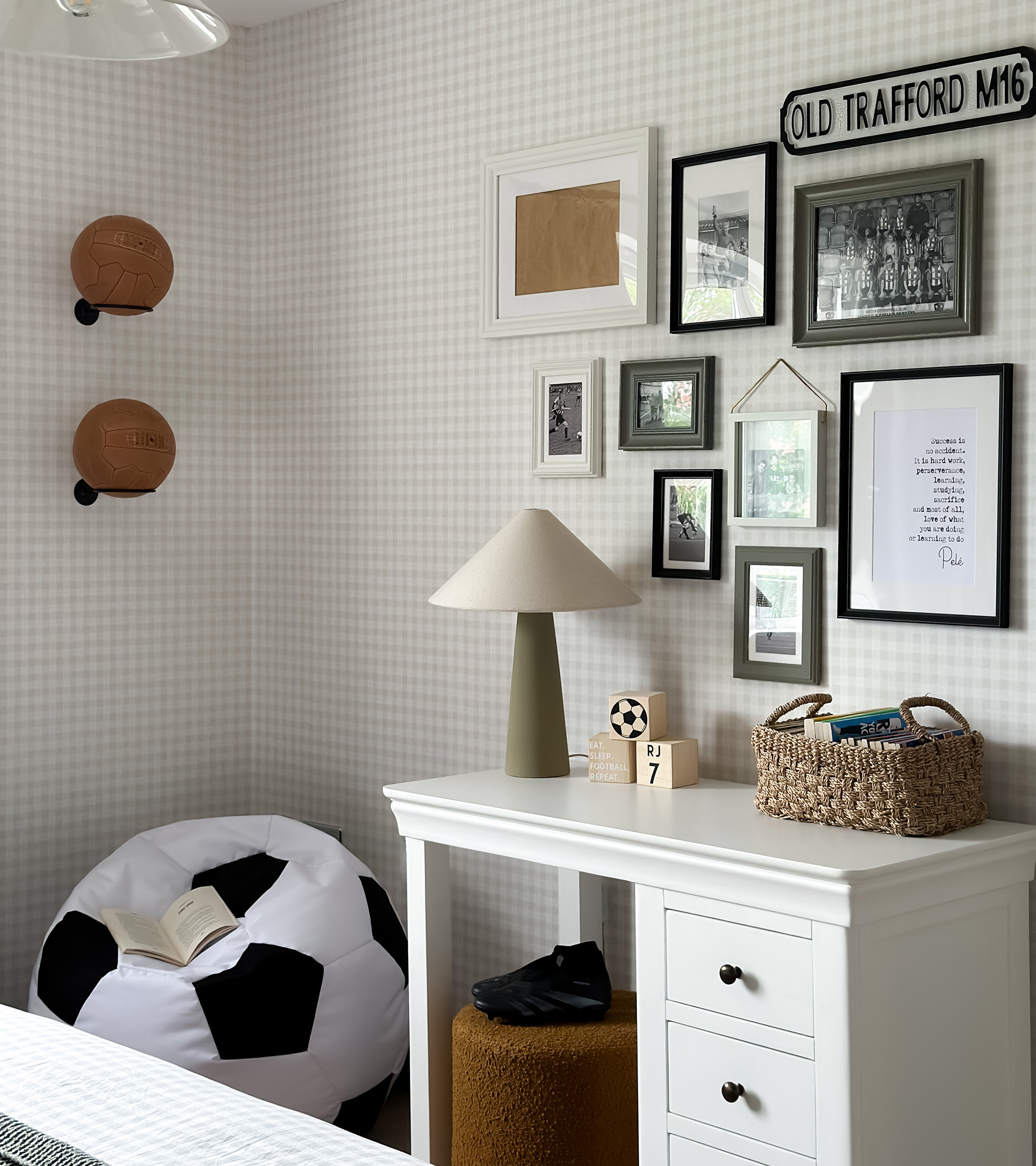 a close up of a childrens bedroom white desk with football memorabilia on the walls