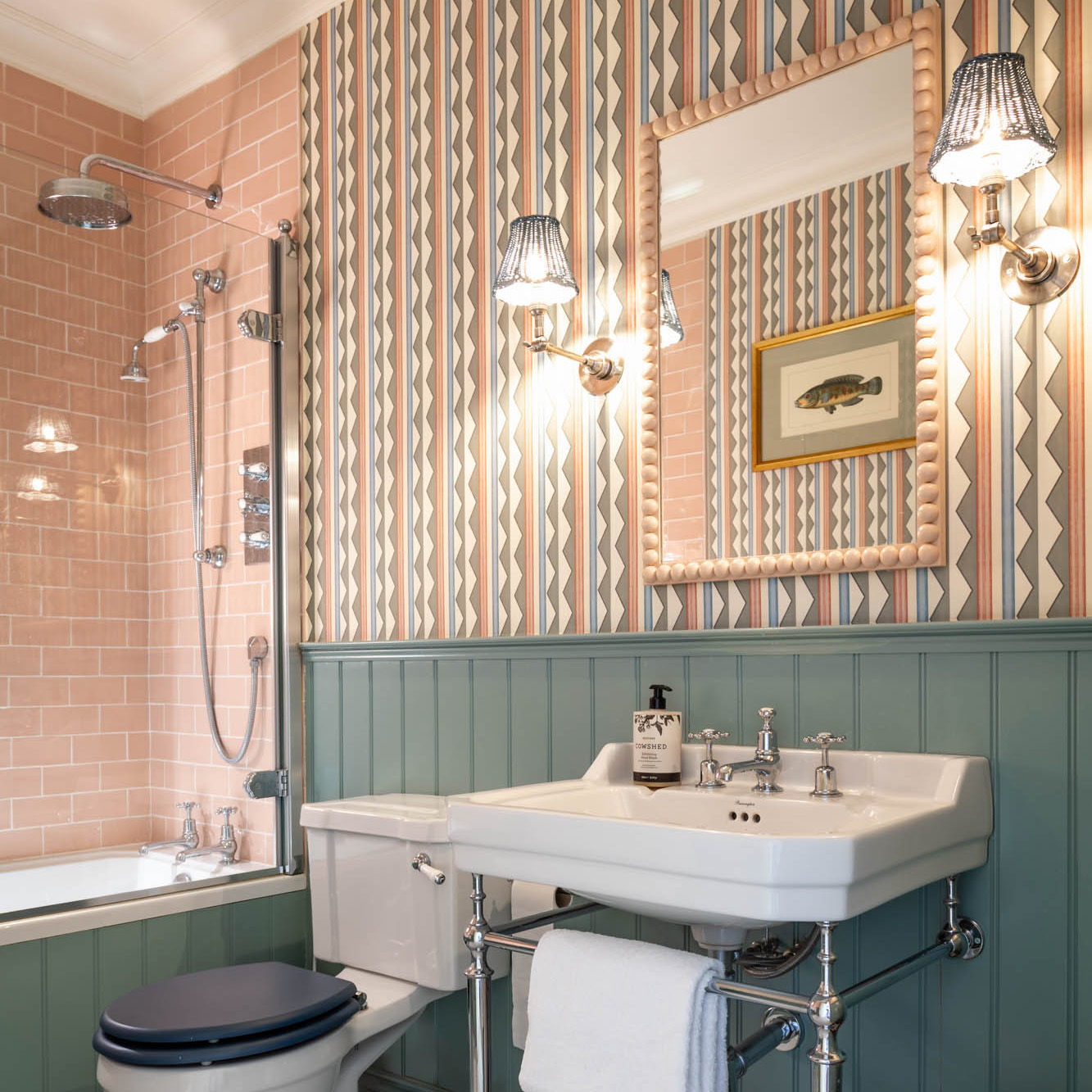bathroom with striped wallpaper a mirror and a fish art print