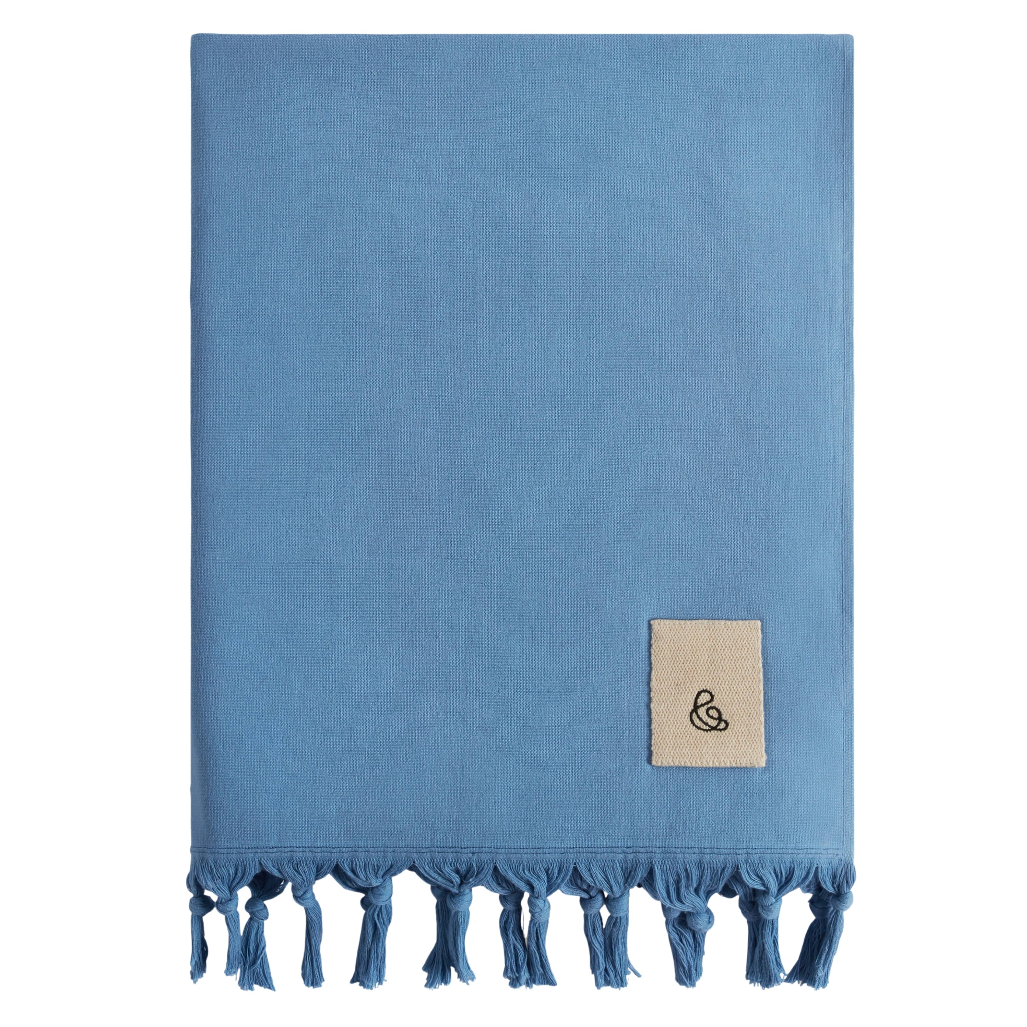 rise and fall Hammam Beach Towel pictured in blue with tassels folded with a white background