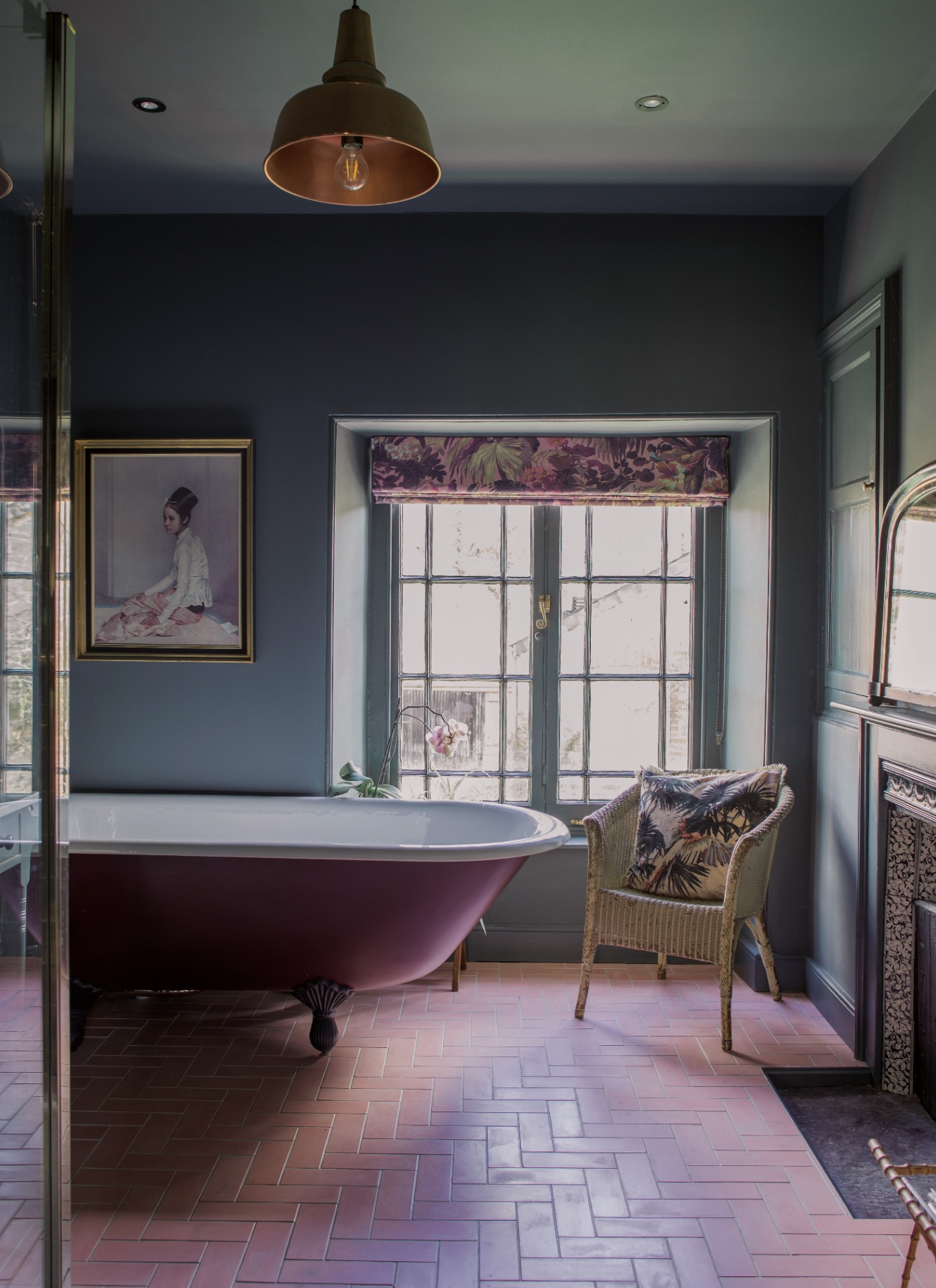 a bathroom with dark teal walls, brick flooring and a large purple freestanding bath tub