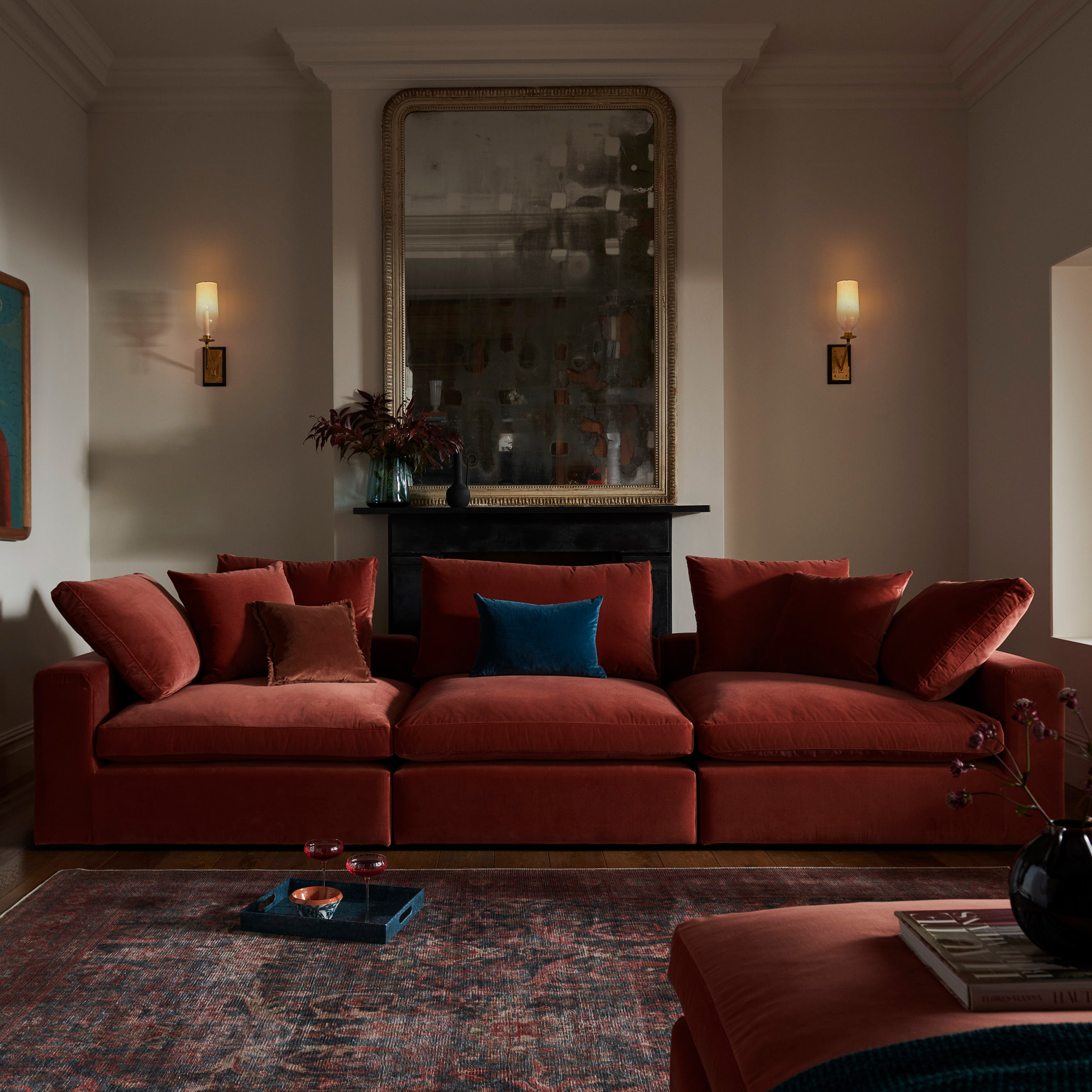 a living room with a dark red sofa and red rug with a big mirror on the wall