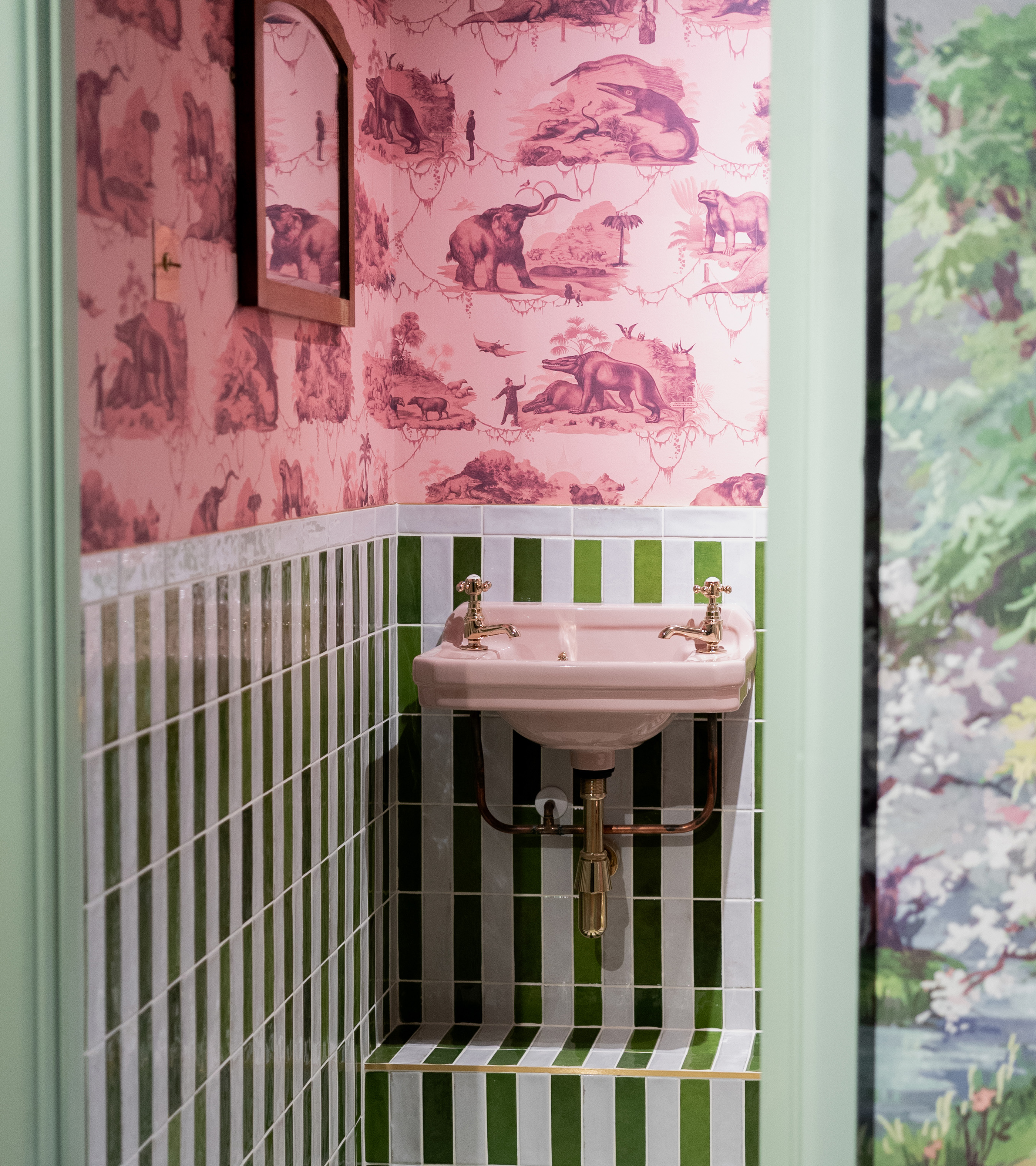 ca pietra small bathroom with a white and green vertical stripe, a pale pink sink and a pink patterned wallpaper