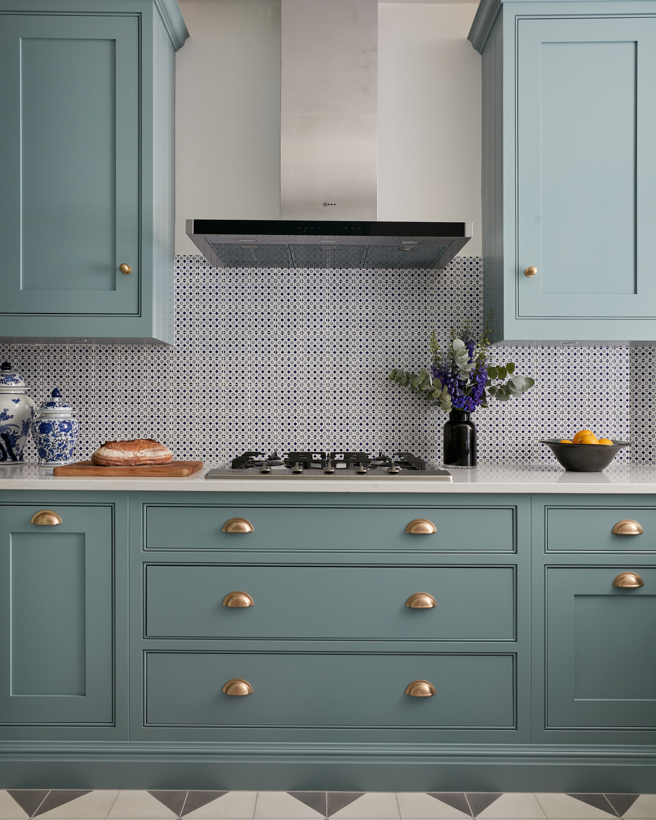 a kitchen with blue cabinets, a patterned tile splashback