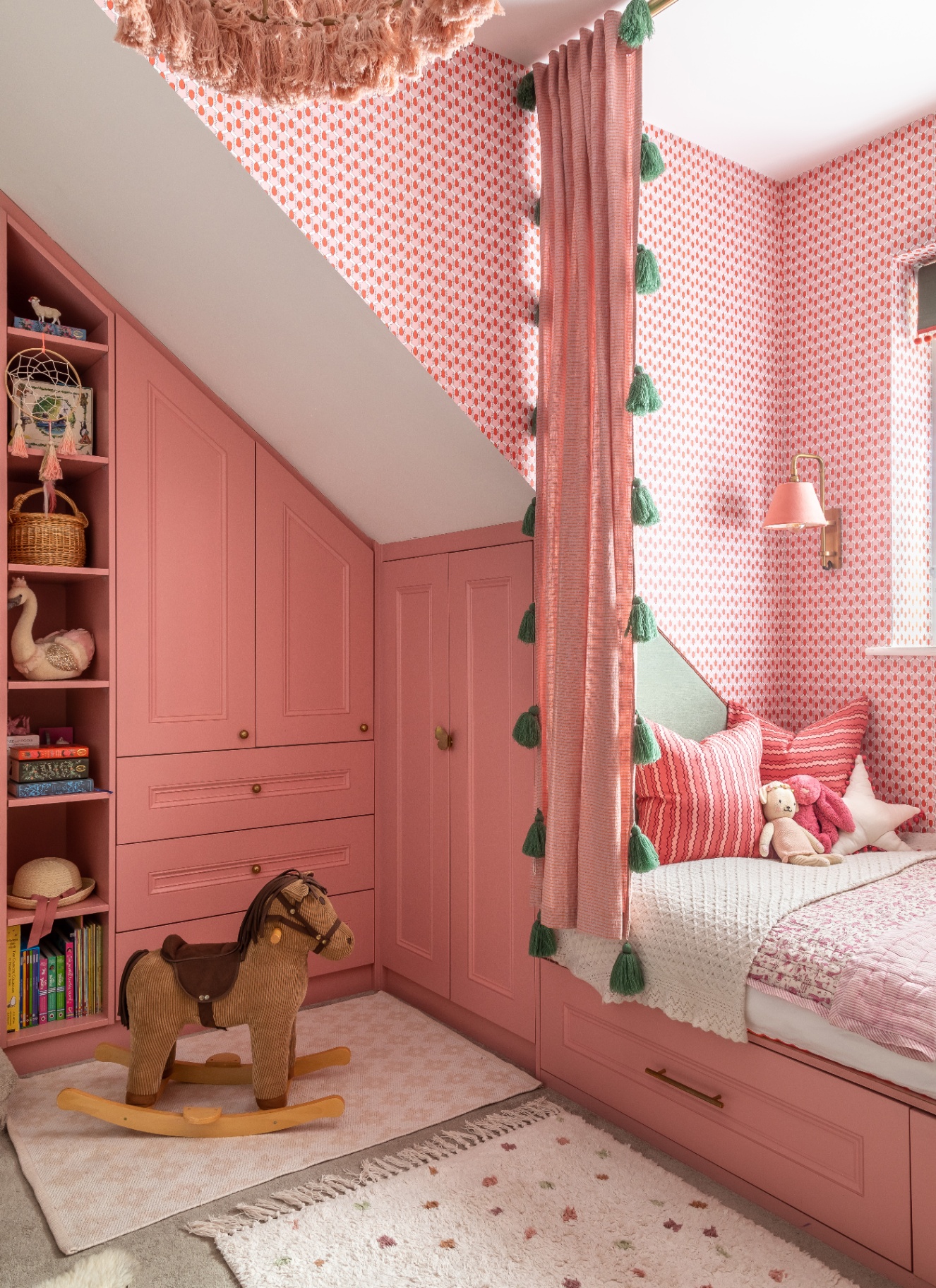 a childrens bedroom with pink painted build in cupboards, a bed nook and a rocking horse