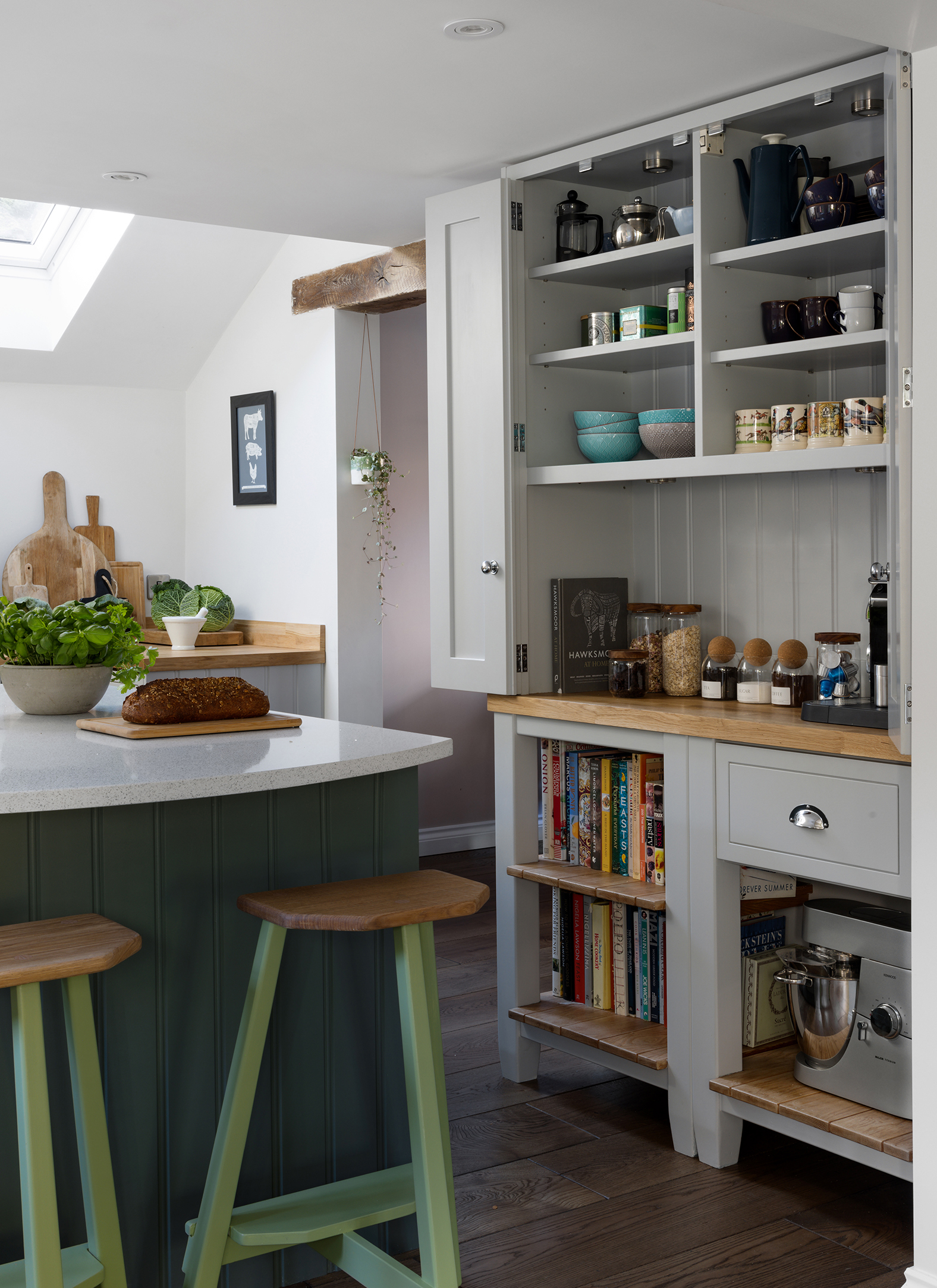 a kitchen with pale grey cabinetry, wooden worktops and a dark green kitchen island with pale green stools