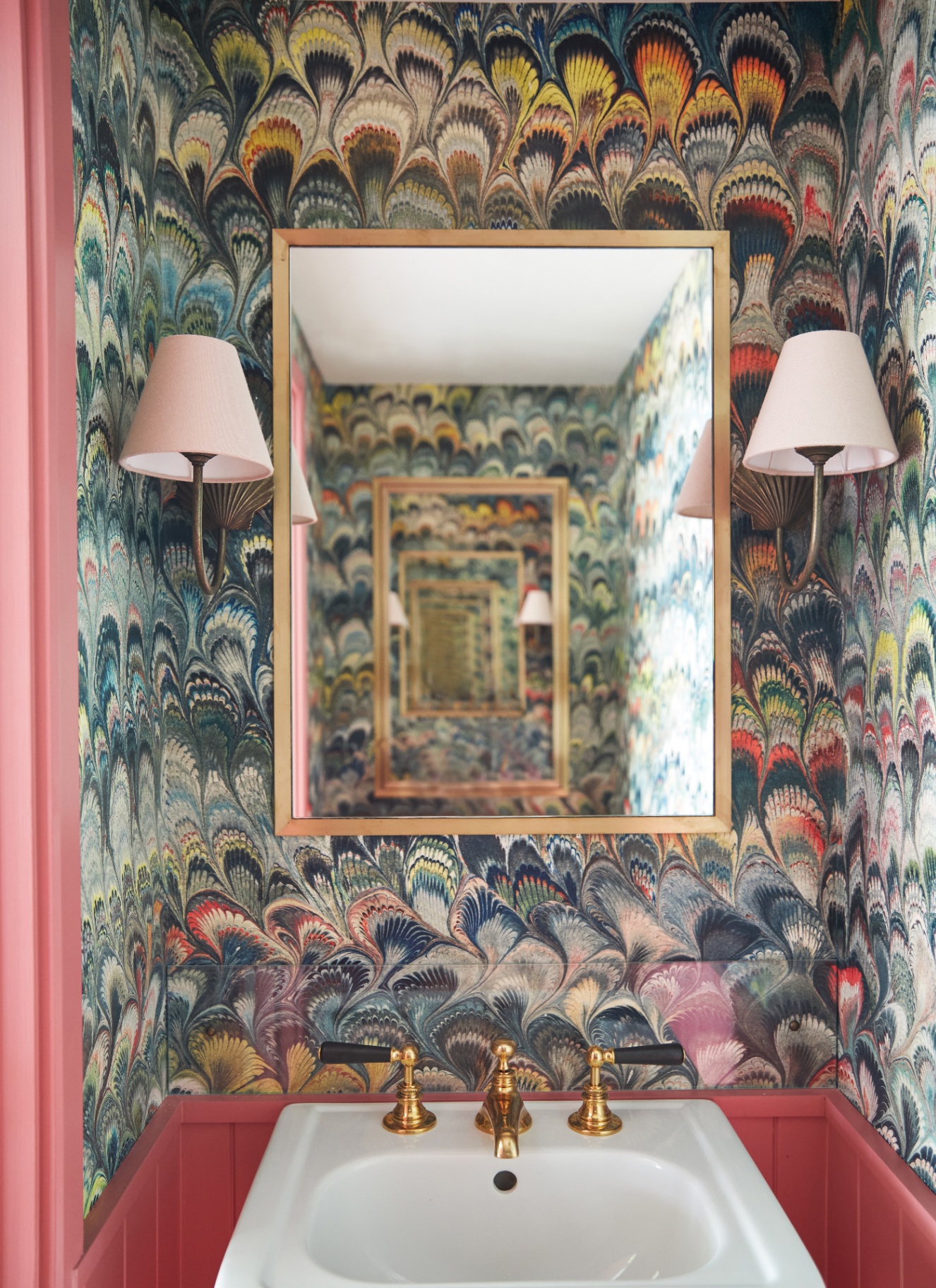 a small downstairs look with colourful marbled wallpaper, a gold mirror and a salmon pink vanity unit