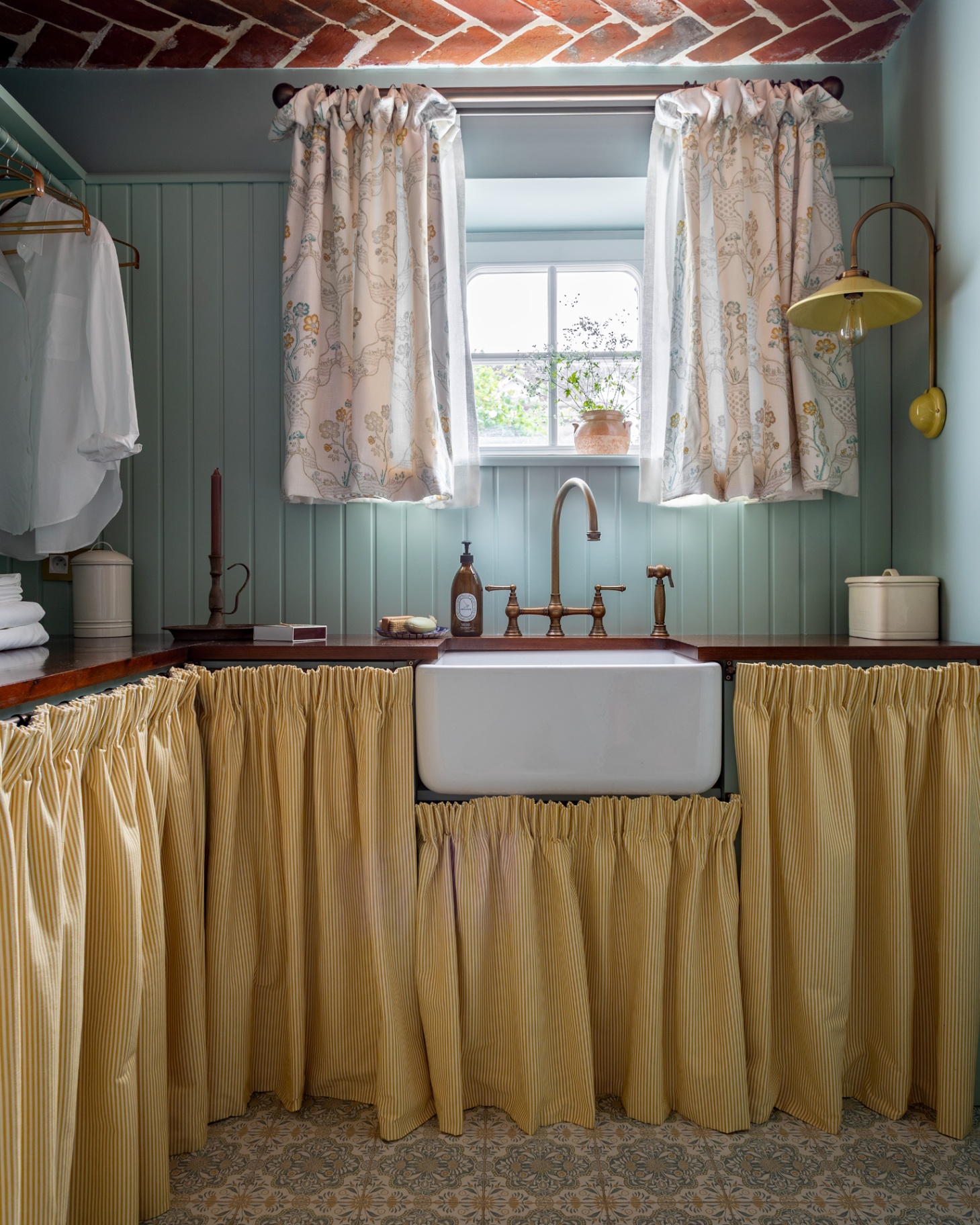 a utility room with a brick ceiling, blue paneled walls, a belfast sink and a yellow stripe wrap around sink skirt