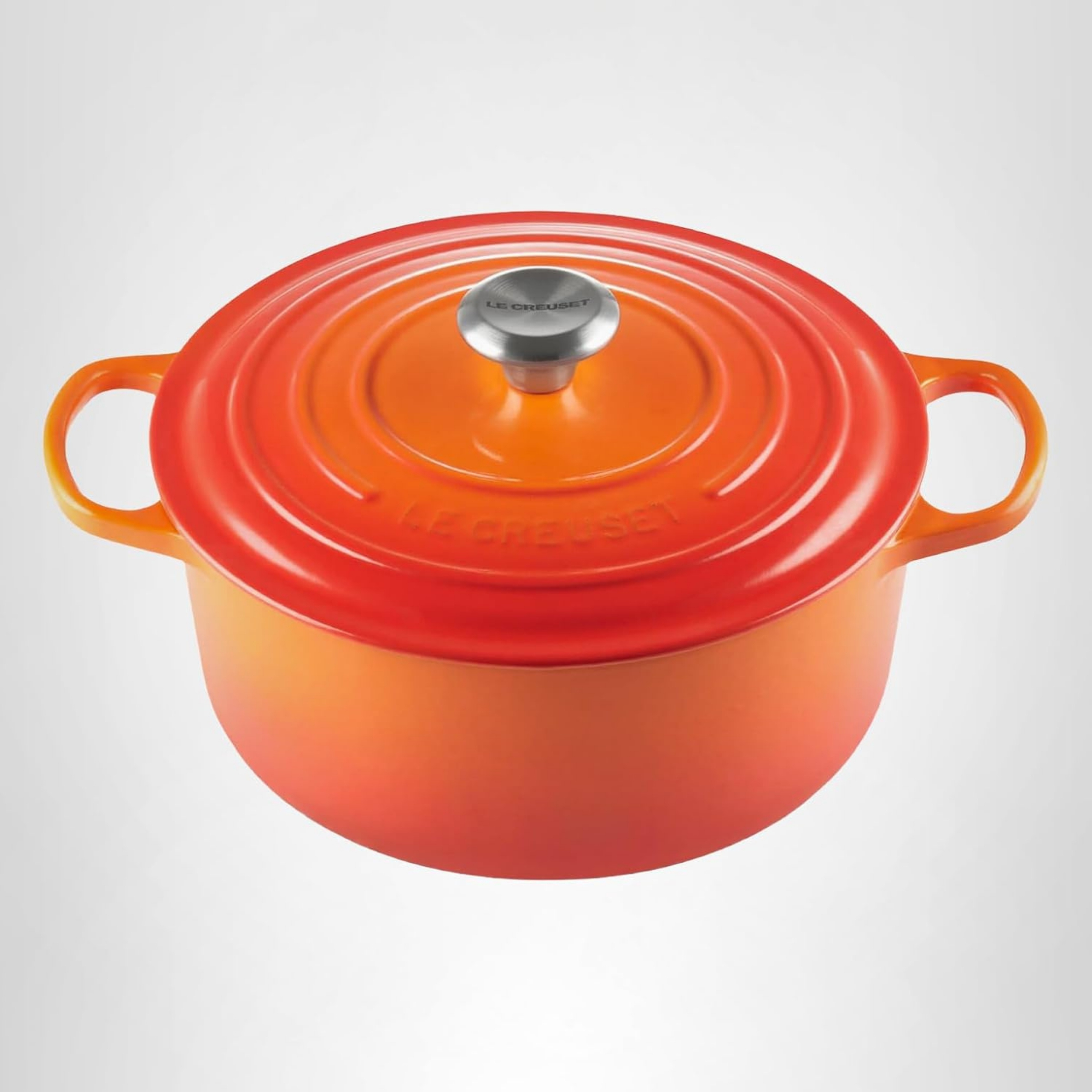 Le Creuset Cast Iron Casserole Dish With Lid pictured in volcanic orange colour on a grey background