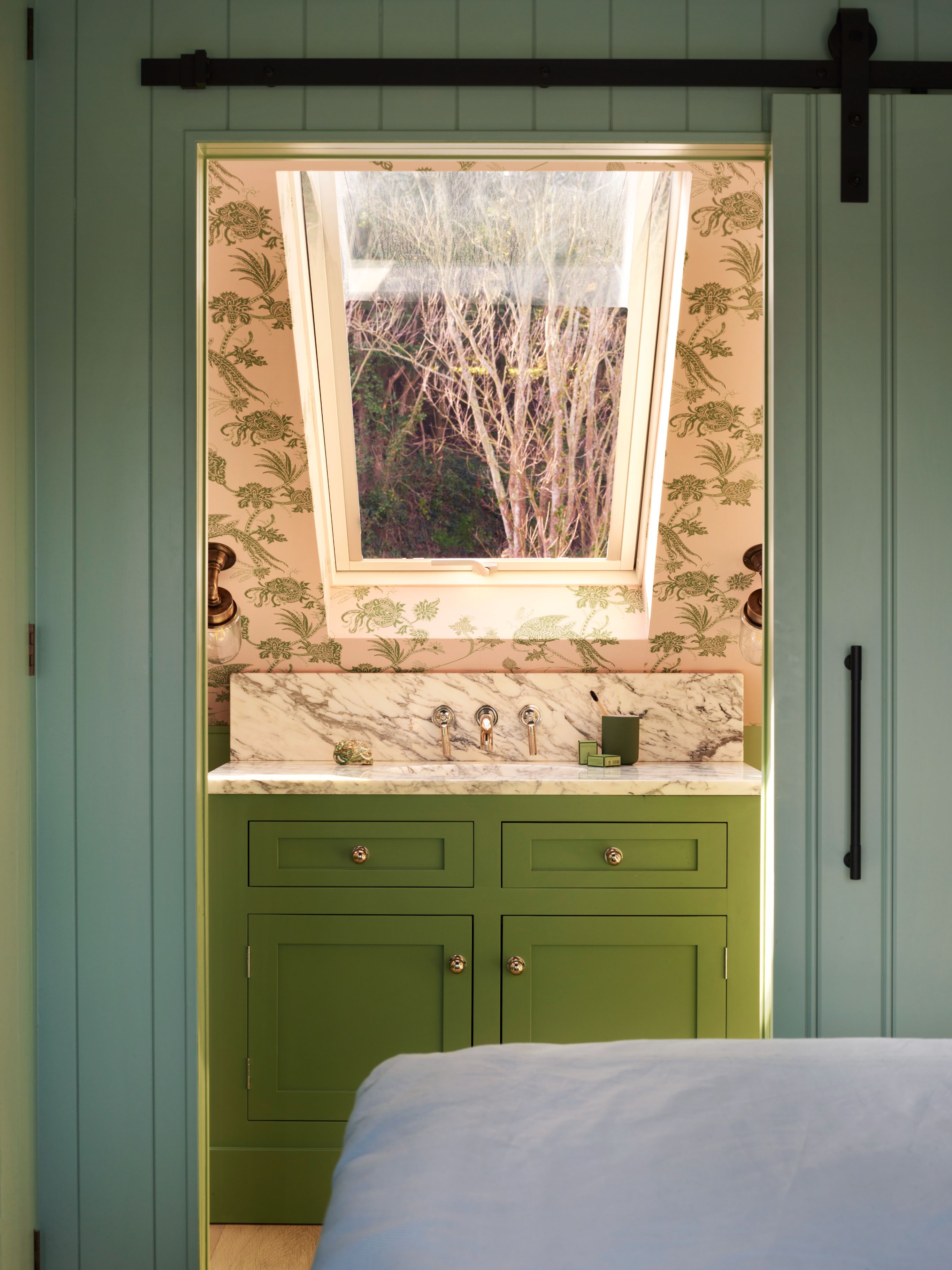 an en suite bathroom pictured with a green marble statement vanity as the focal point, also featured is bold bathroom wallpaper