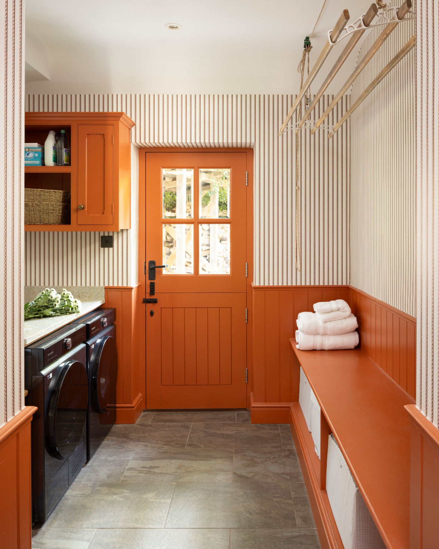 a utility room with half orange paneled walls and half stripe wallpaper