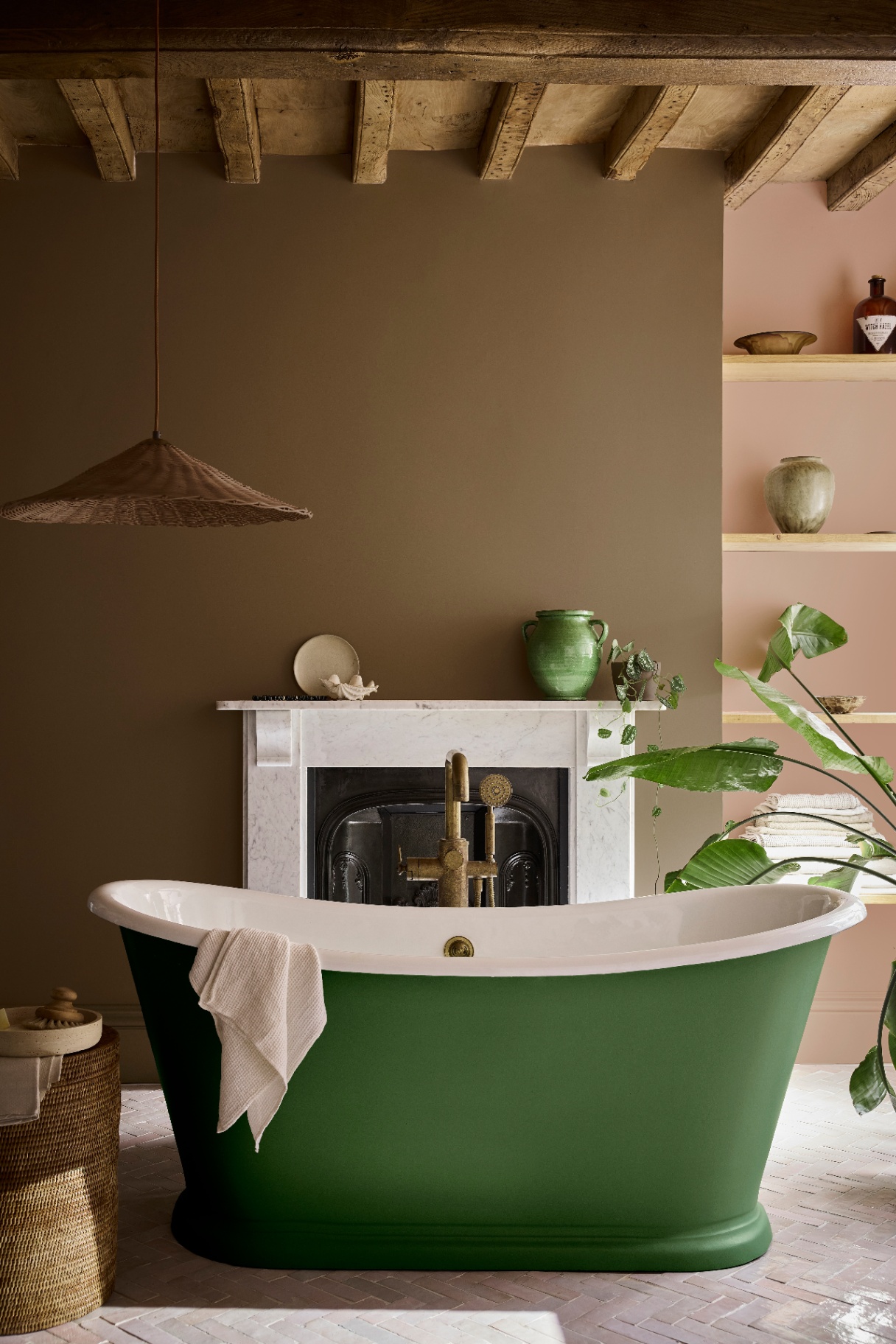 a bathroom pictured with a green statement bath the ceiling is made from wood and the walls are painted brown and pink, featuring marle