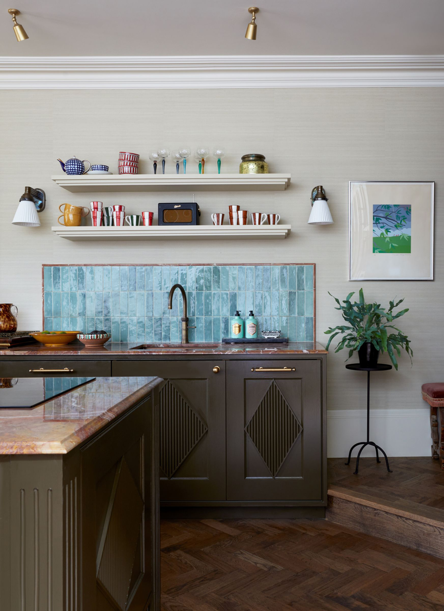 a kitchen with dark painted cabinets, a blue zellige tile splash back and two open shelves above it with striped cups and a roberts radio