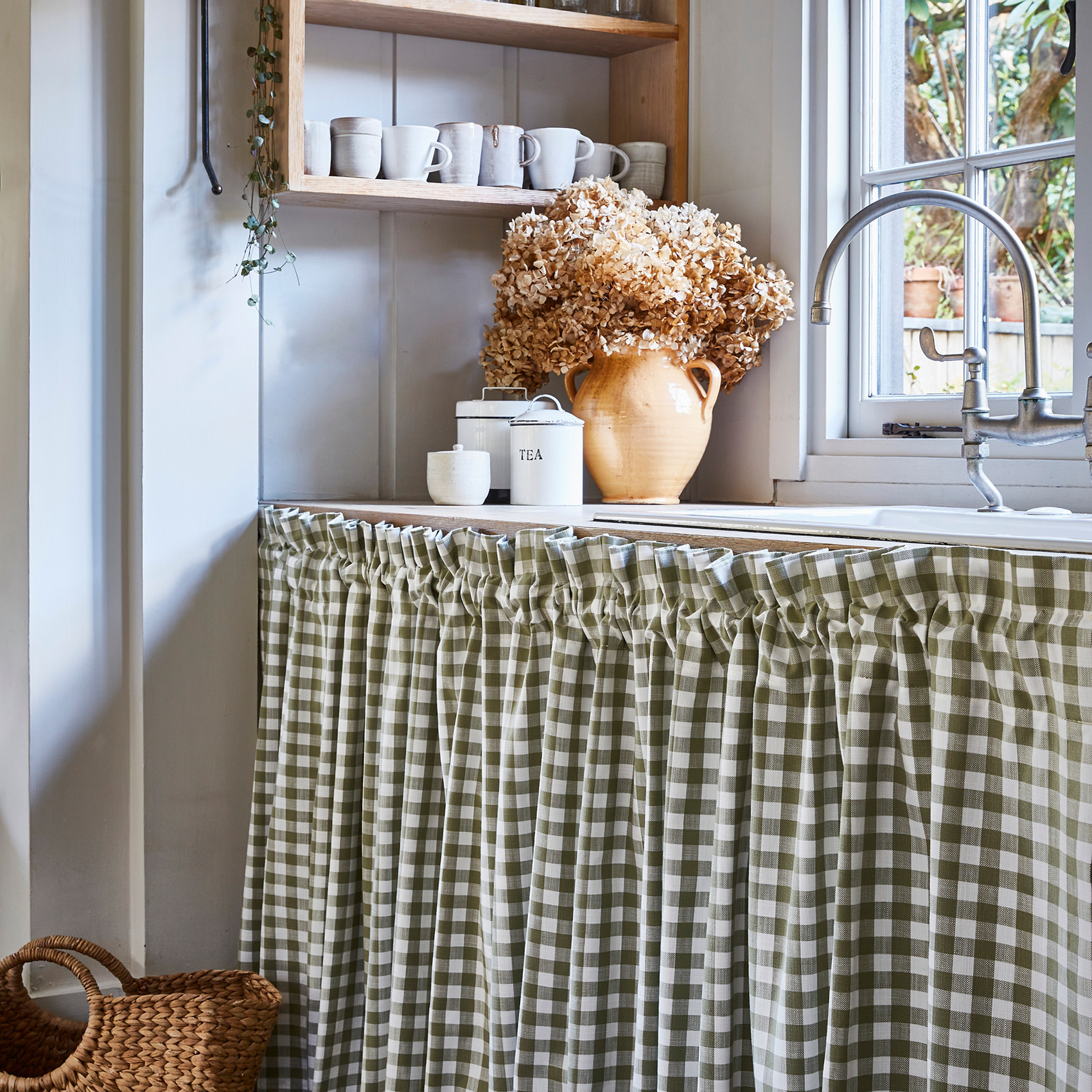 a white kitchen with a green gingham sink skirt