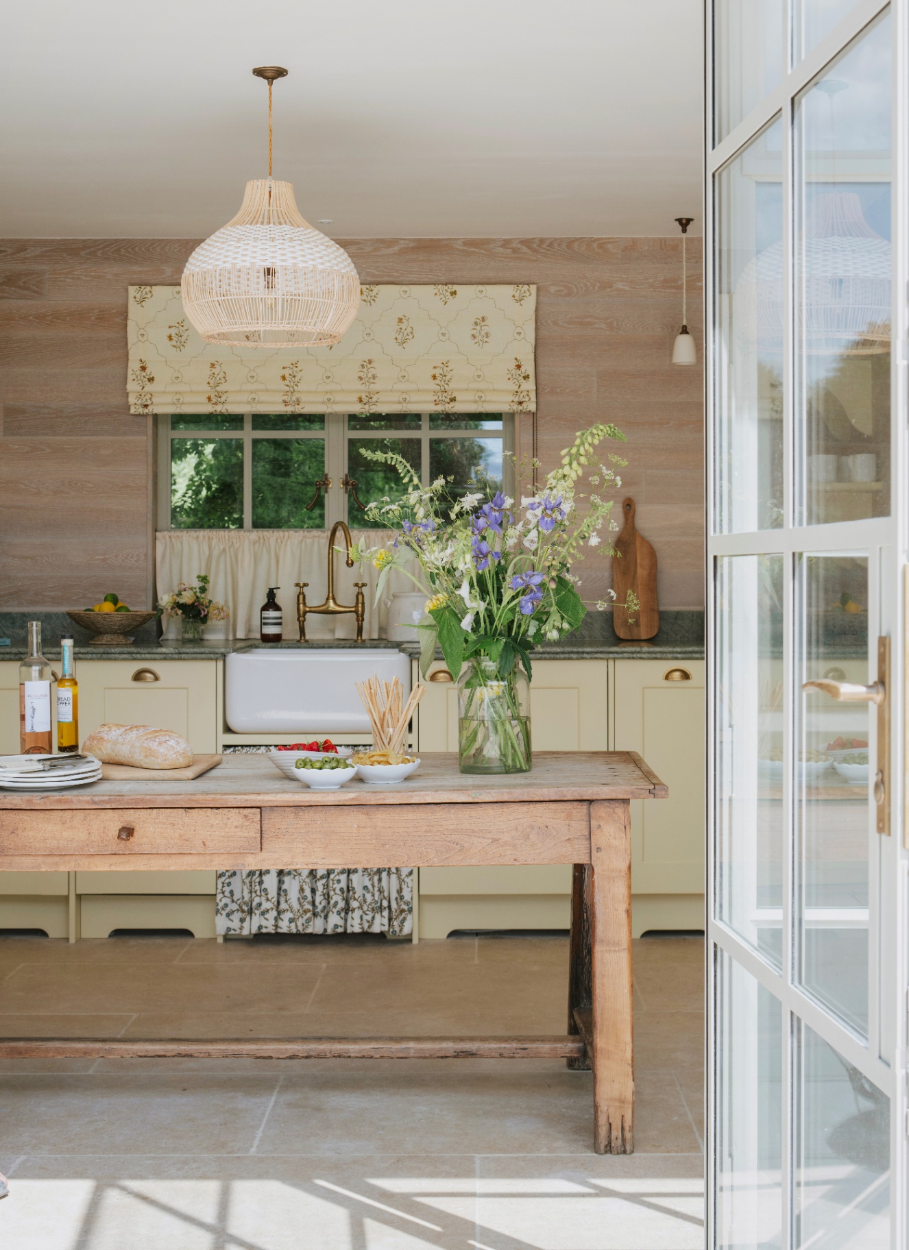 interior of a poolhouse with pale yellow cabinets and a large wooden kitchen island