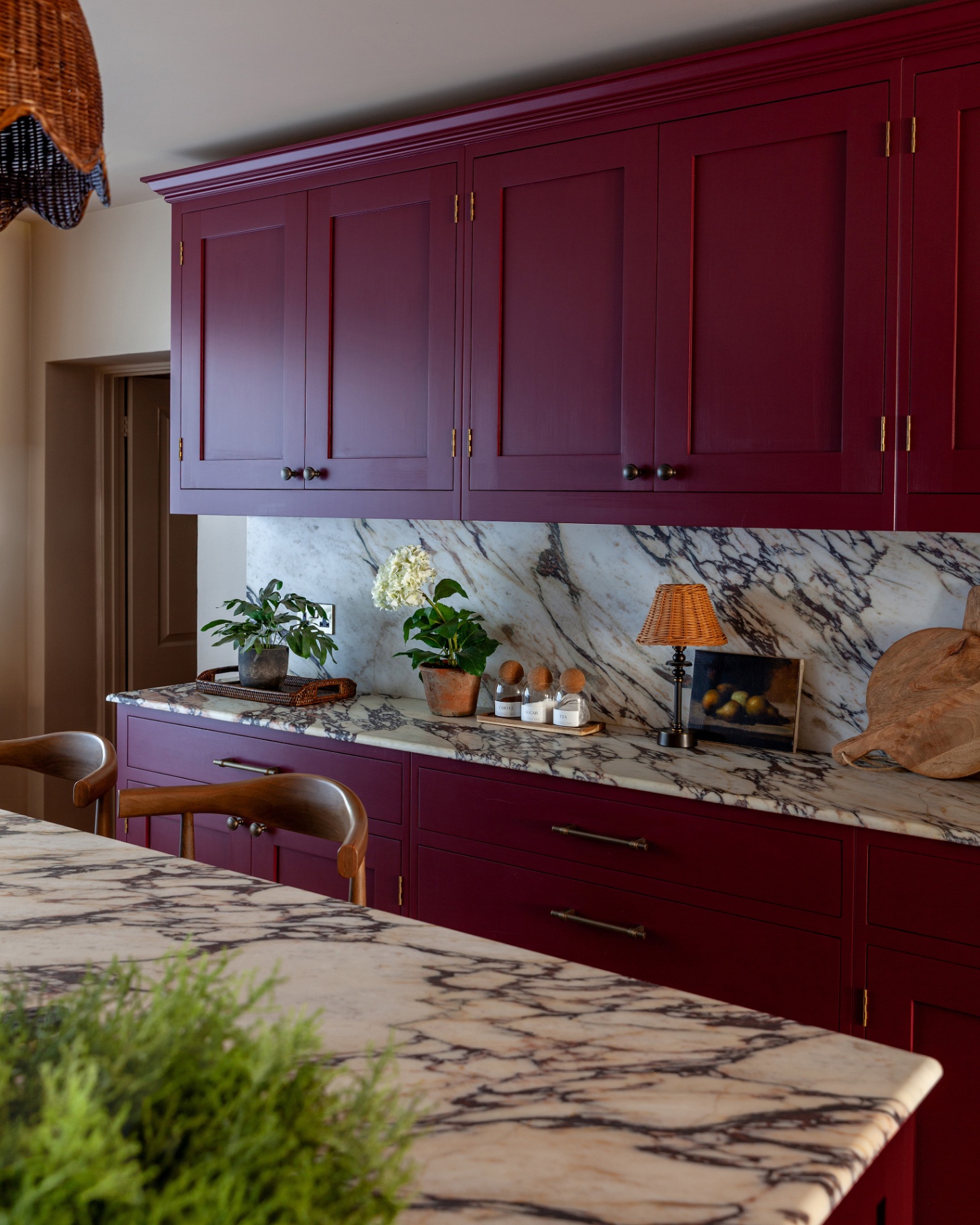 a kitchen with deep red kitchen cabinets and grey and white marble worktops and splashback